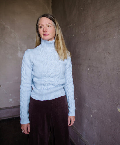 Woman wearing Vanessa Bruno dabatha cable knit turtleneck sweater in shade azure merino wool blend