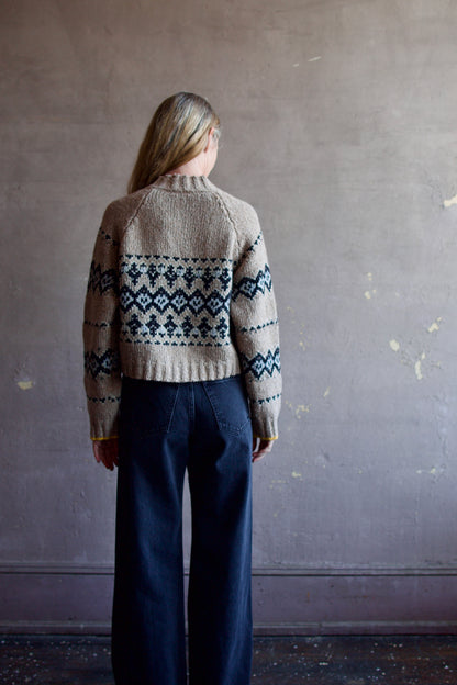 Image featuring a woman wearing the Damas khaki sweater by Vanessa Bruno in black and baby blue argyle pattern with small yellow detail trim at sleeve.