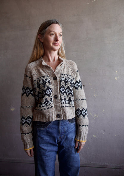 Image featuring a woman wearing the Damas khaki sweater by Vanessa Bruno in black and baby blue argyle pattern with small yellow detail trim at sleeve.