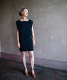 Image featuring a woman wearing the Dorotea dress by Vanessa Bruno with a boatneck, boxy shoulders, short skirt and a tailored body in navy blue.