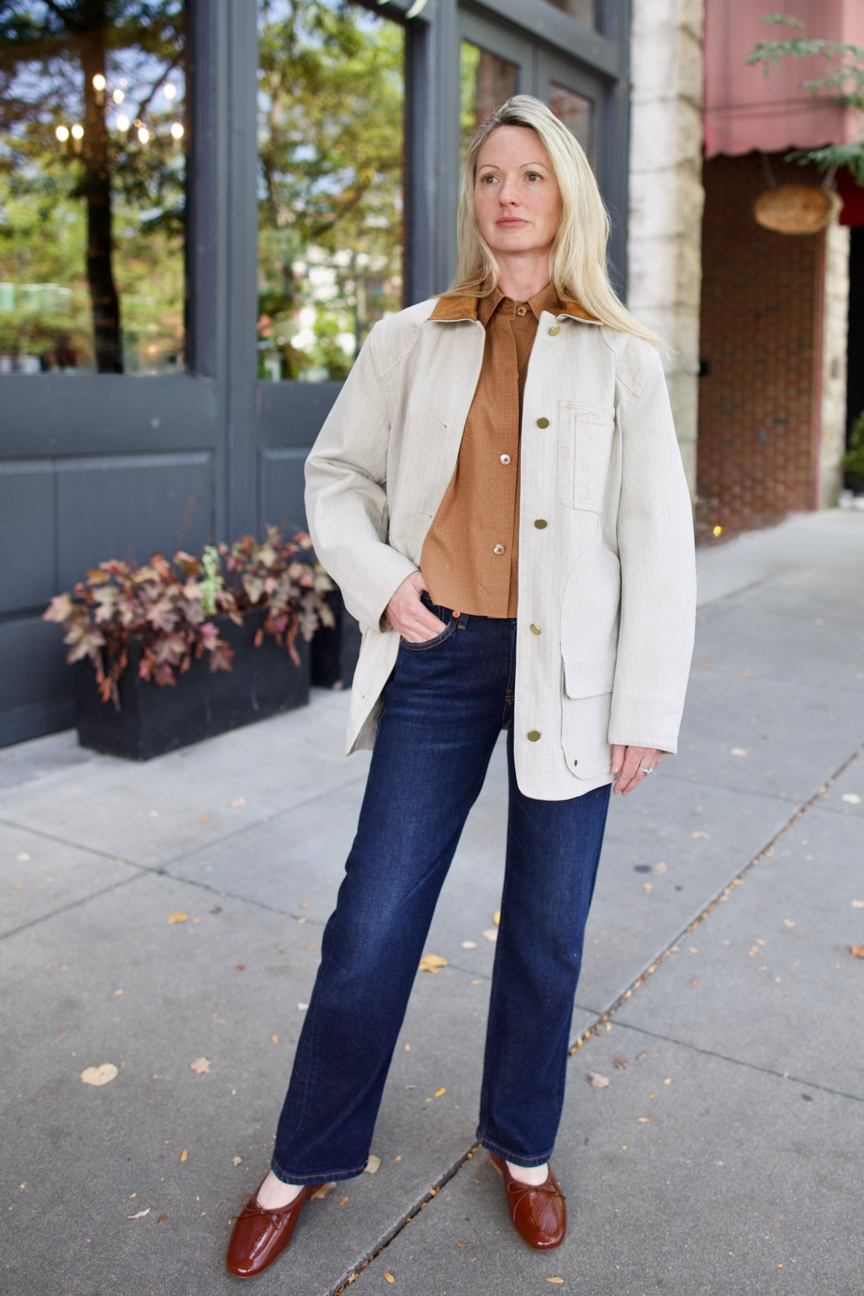Model wearing a light weight cotton neutral barn jacket with a suede collar over a TWP shirt and denim.