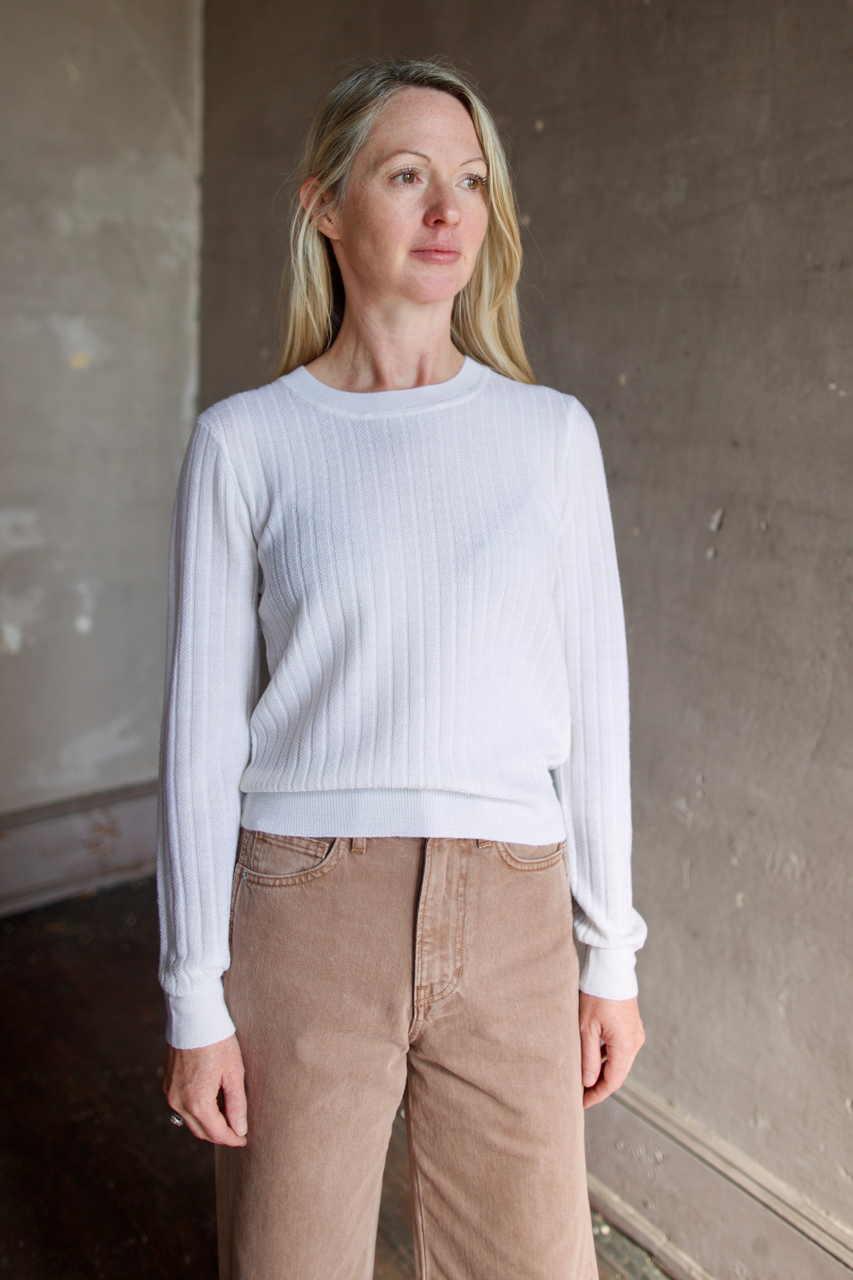Model wearing Veronica Beard premium wool cheval pullover in ivory with lightweight wide ribbed texture, long sleeves, and crew neck