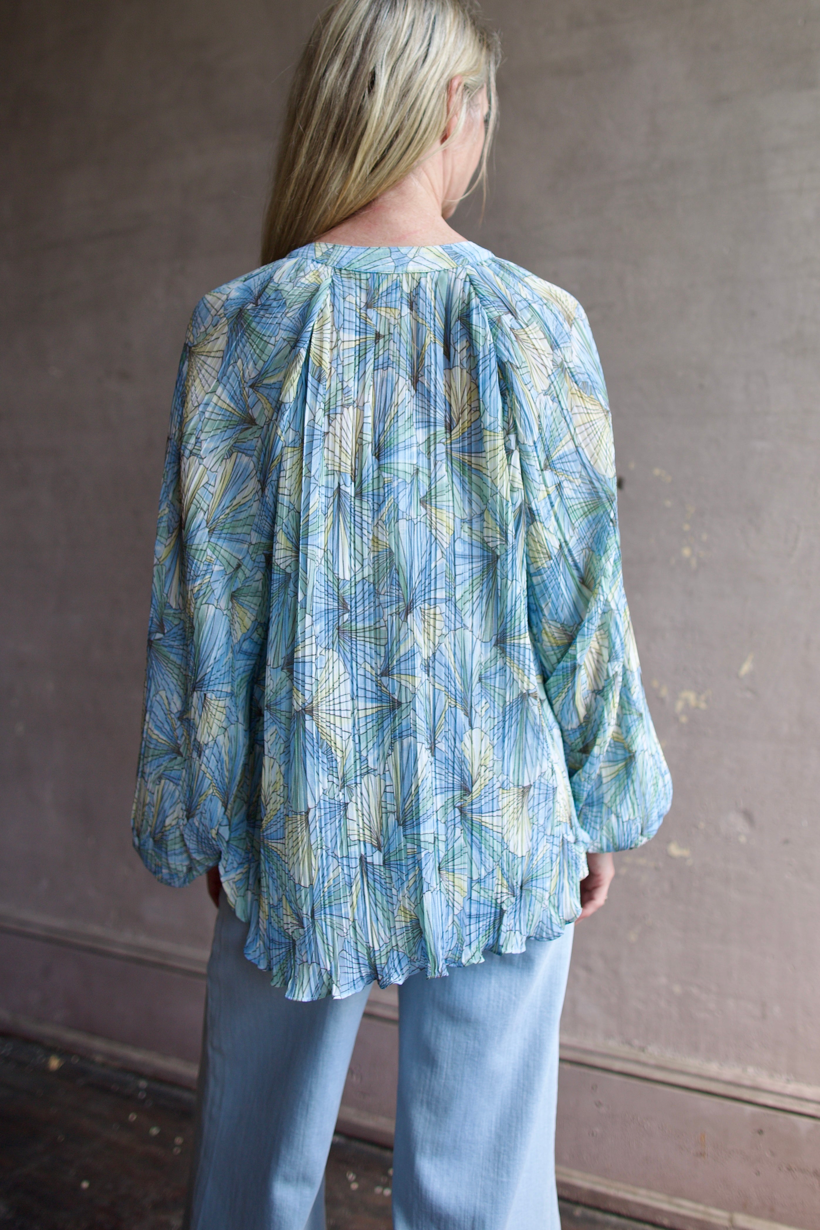 Mature womanl wearing designer Veronica Beard Fennel Pleated Blouse with long sleeve in flowy effortless Bohemian style and wrinkle free perfect to pack for vacation