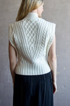 Image featuring a woman wearing the Holton Knit Vest by Veronica Beard with a mock neck, button detailing down left shoulder and intricate knit wool detailing in cream.