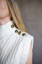 Image featuring a woman wearing the Holton Knit Vest by Veronica Beard with a mock neck, button detailing down left shoulder and intricate knit wool detailing in cream.