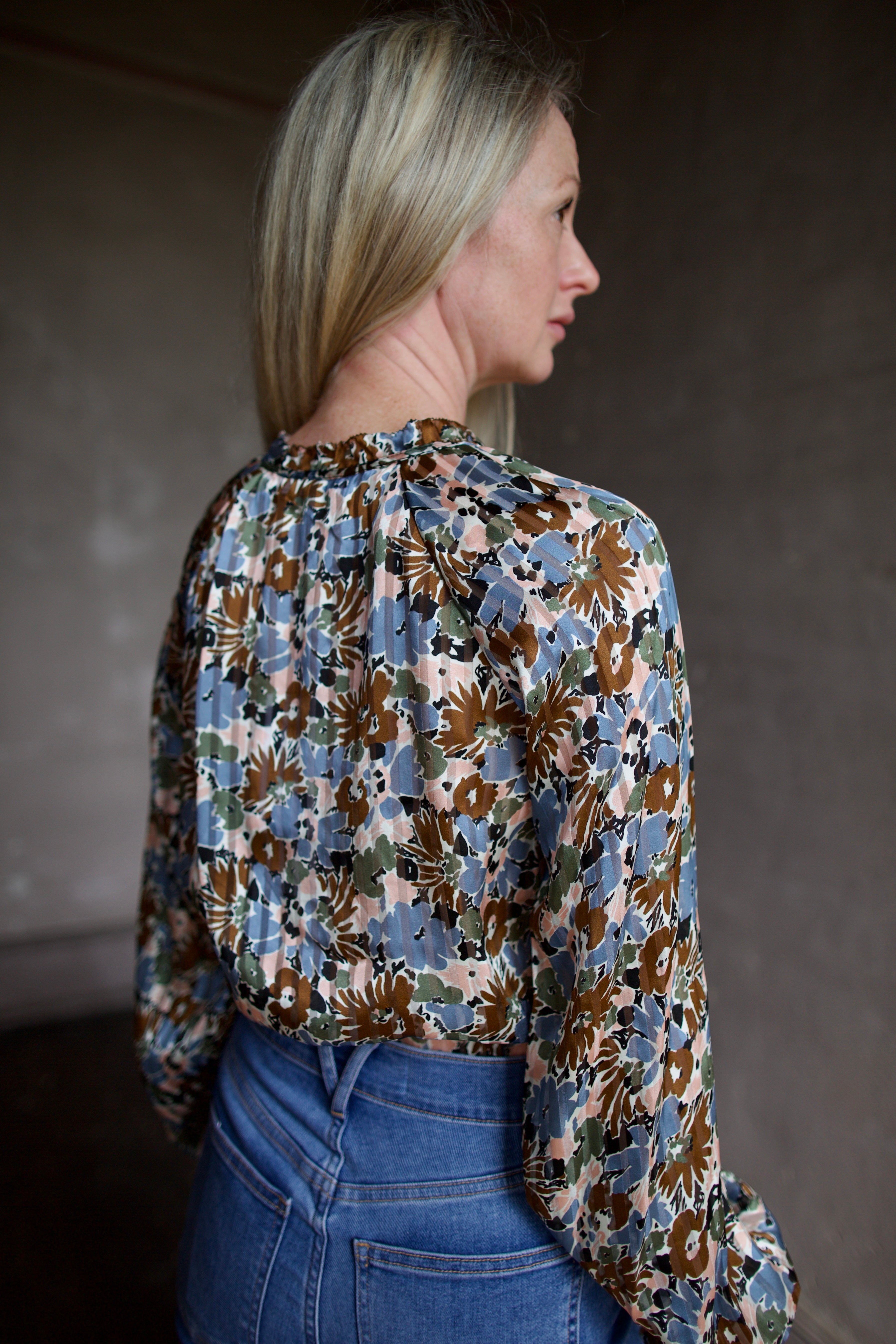 Mature model wearing elevated  designer Veronica Beard silk Linds Blouse in lake mist multi with blouson sleeves and v-neck with tie closure