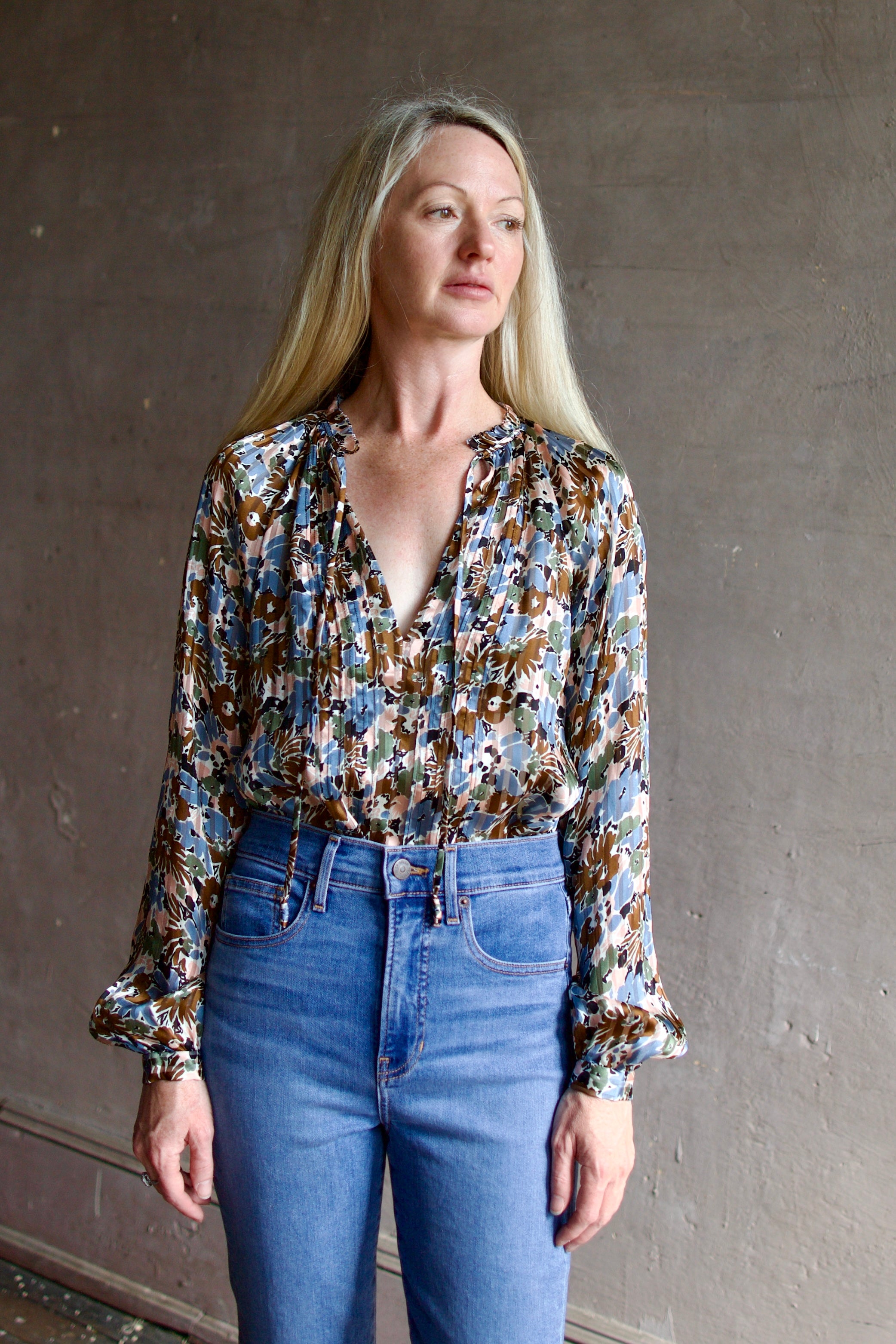 Mature model wearing contemporary designer Veronica Beard silk Linds Blouse in lake mist multi with blouson sleeves and v-neck with tie closure