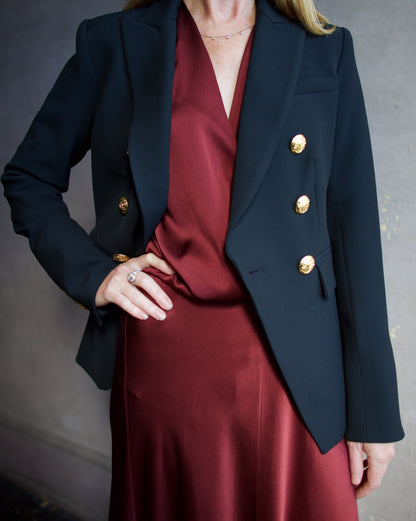 Image featuring a woman wearing the Miller Dickey Jacket by Veronica Beard with a double breasted closure and tailored fit in black with gold color buttons.