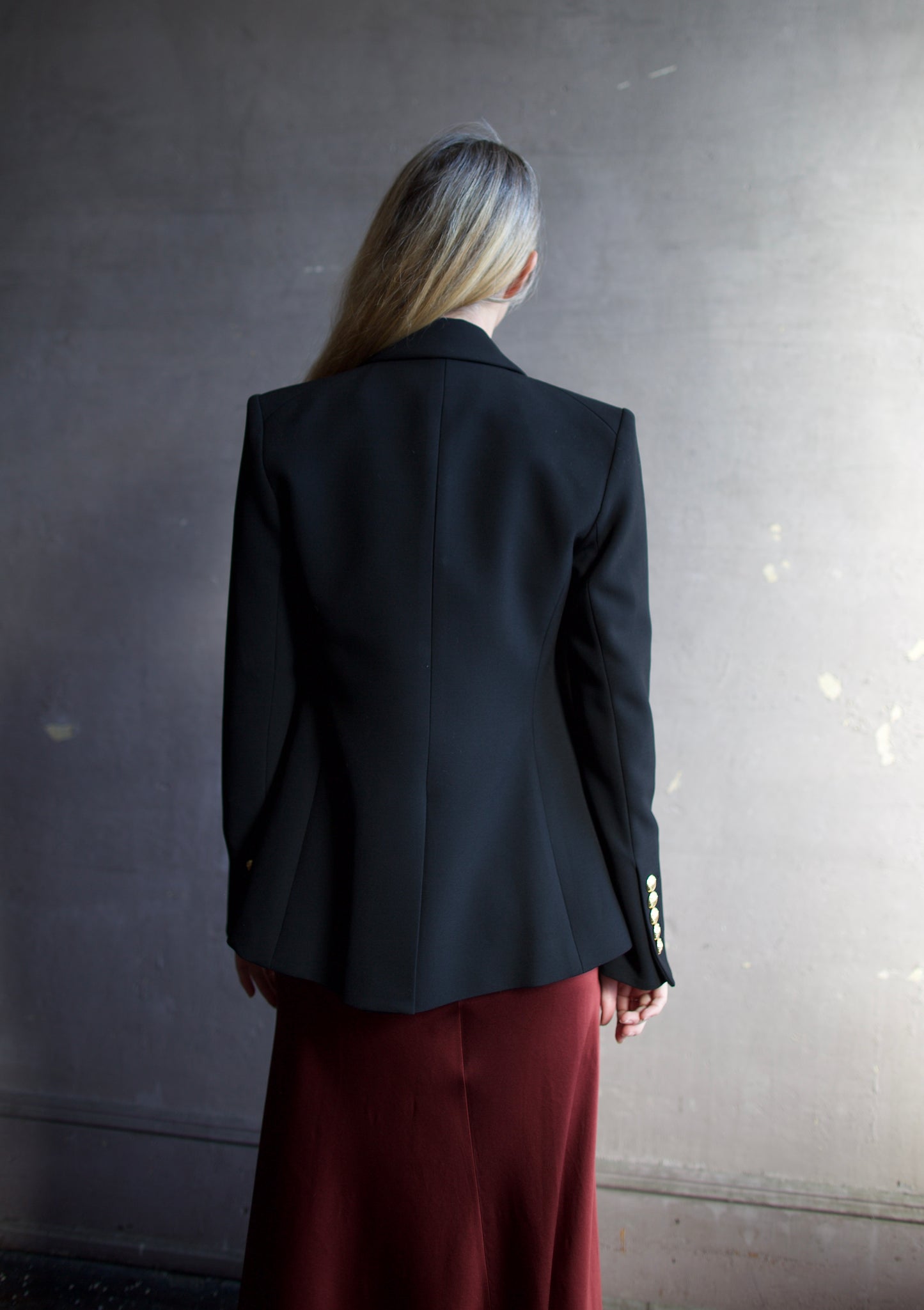 Image featuring a woman wearing the Miller Dickey Jacket by Veronica Beard with a double breasted closure and tailored fit in black with gold color buttons.