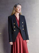 Image featuring a woman wearing the Miller Dickey Jacket by Veronica Beard with a double breasted closure and tailored fit in black with gold color buttons.