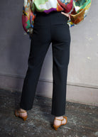 Image featuring a woman wearing the Renzo Pants by Veronica Beard with a tab waistband with a mid rise and straight leg in black with gold finish buttons.