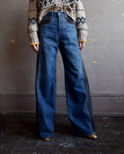 Image featuring a woman wearing the Taylor jeans by Veronica Beard with a high rise, wide leg and a two tone wash. Fabricated in blue denim front and black denim sides & back.