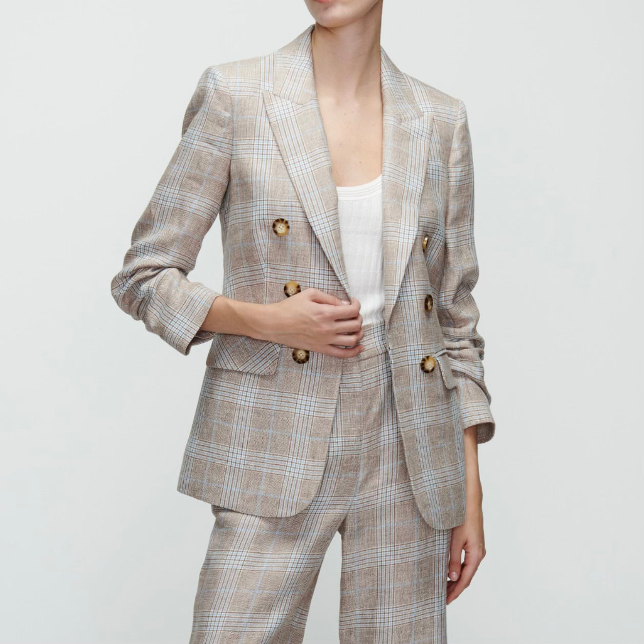 Image featuring a woman wearing the Beacon double-breasted plaid blazer by Veronica Beard with pre-ruched sleeves, peak lapels and flap pockets. 