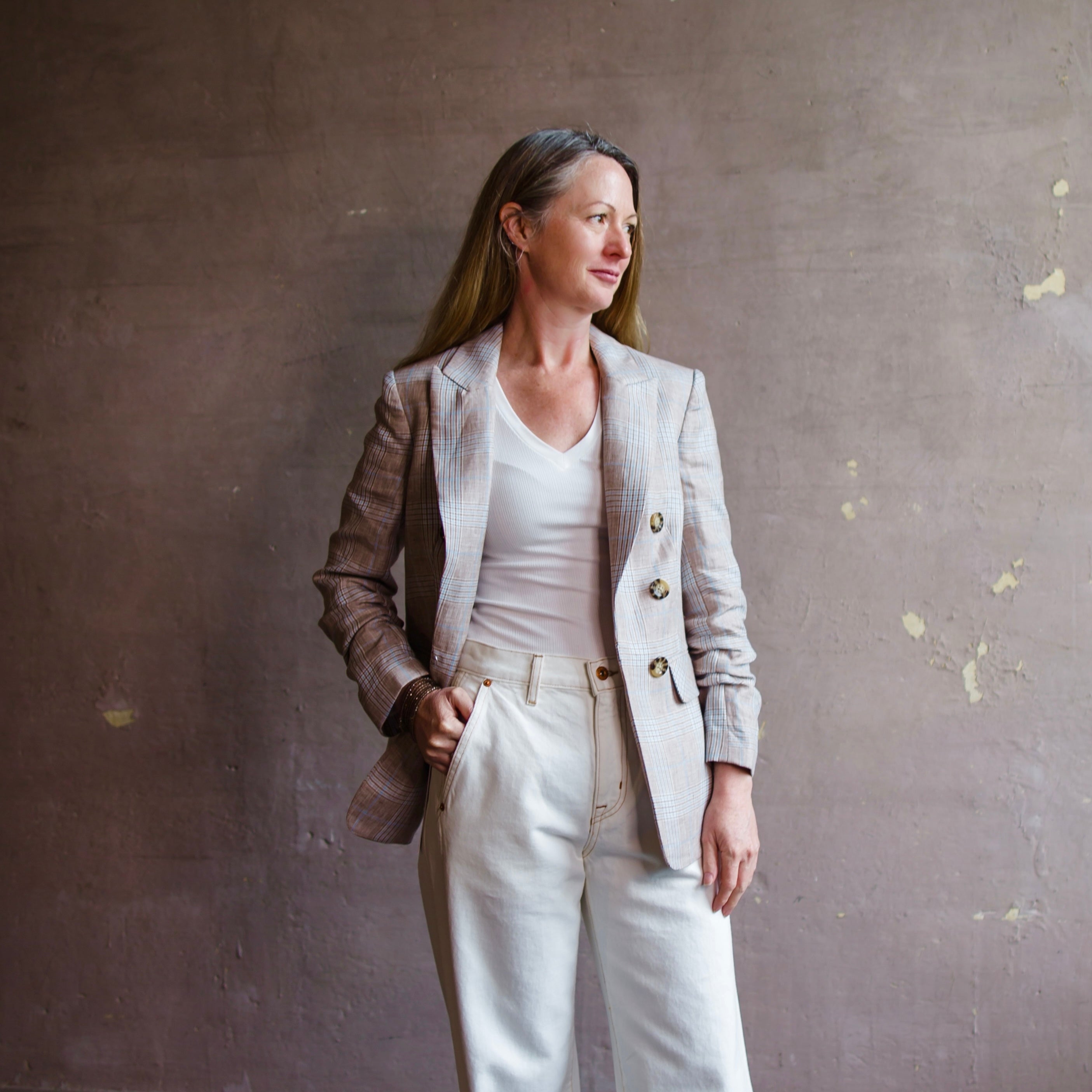 Image featuring a woman wearing the Beacon double-breasted plaid blazer by Veronica Beard with pre-ruched sleeves, peak lapels and flap pockets. 