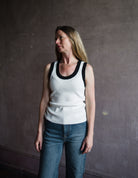 Image featuring a woman wearing the white Sandra Scalloped top by Veronica Beard with a scoop neckline and black scalloped trim to add a feminine touch.