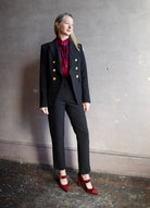 Image featuring a woman wearing the Miller Dickey Jacket by Veronica Beard with a double breasted closure and tailored fit in black with gold color buttons.