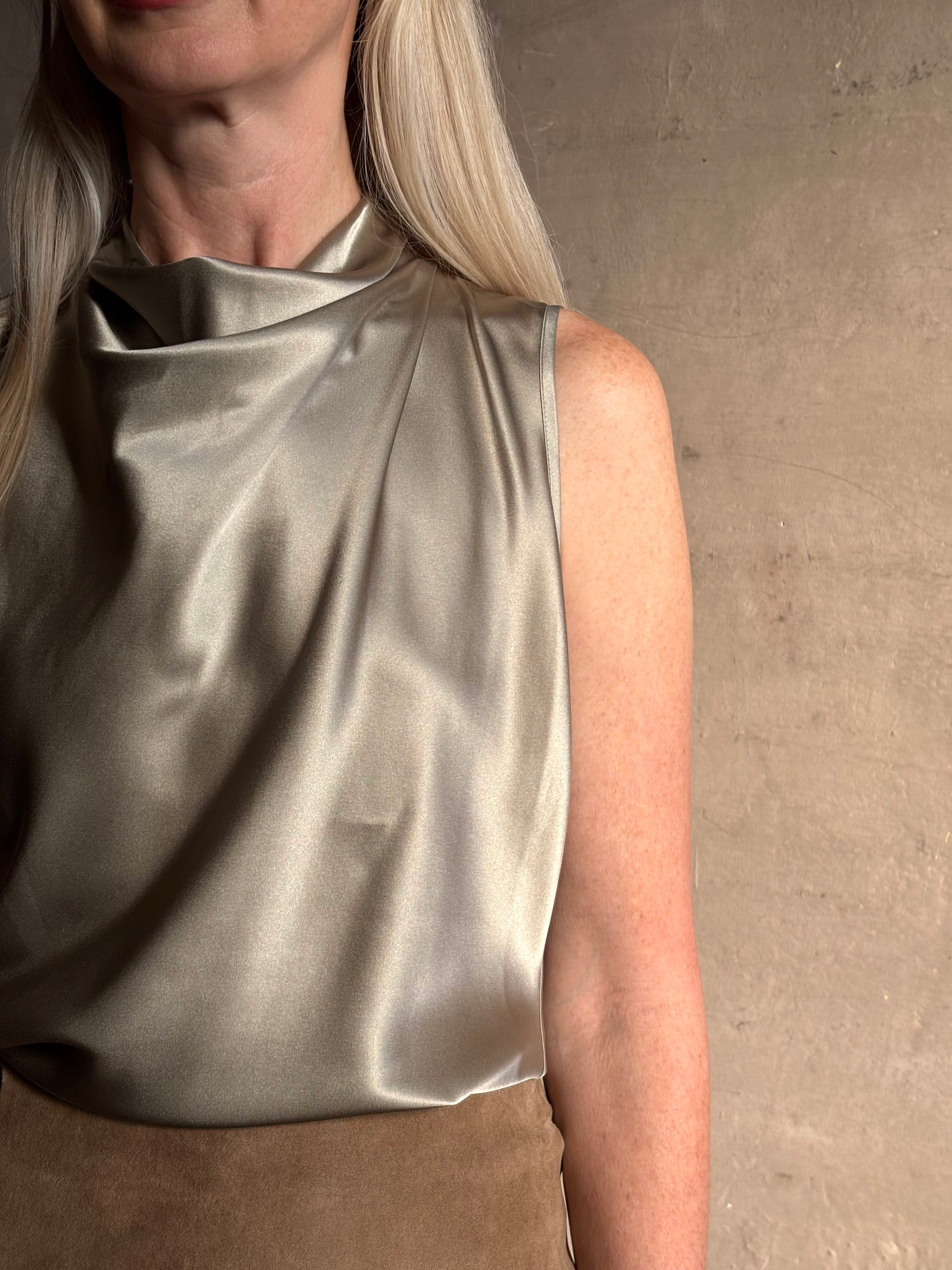Close-up image showing mature woman wearing a pewter colored Veronica Beard Tam Top with a beautifully draped waterfall neckline there's an intigrated weight to keep draping in place