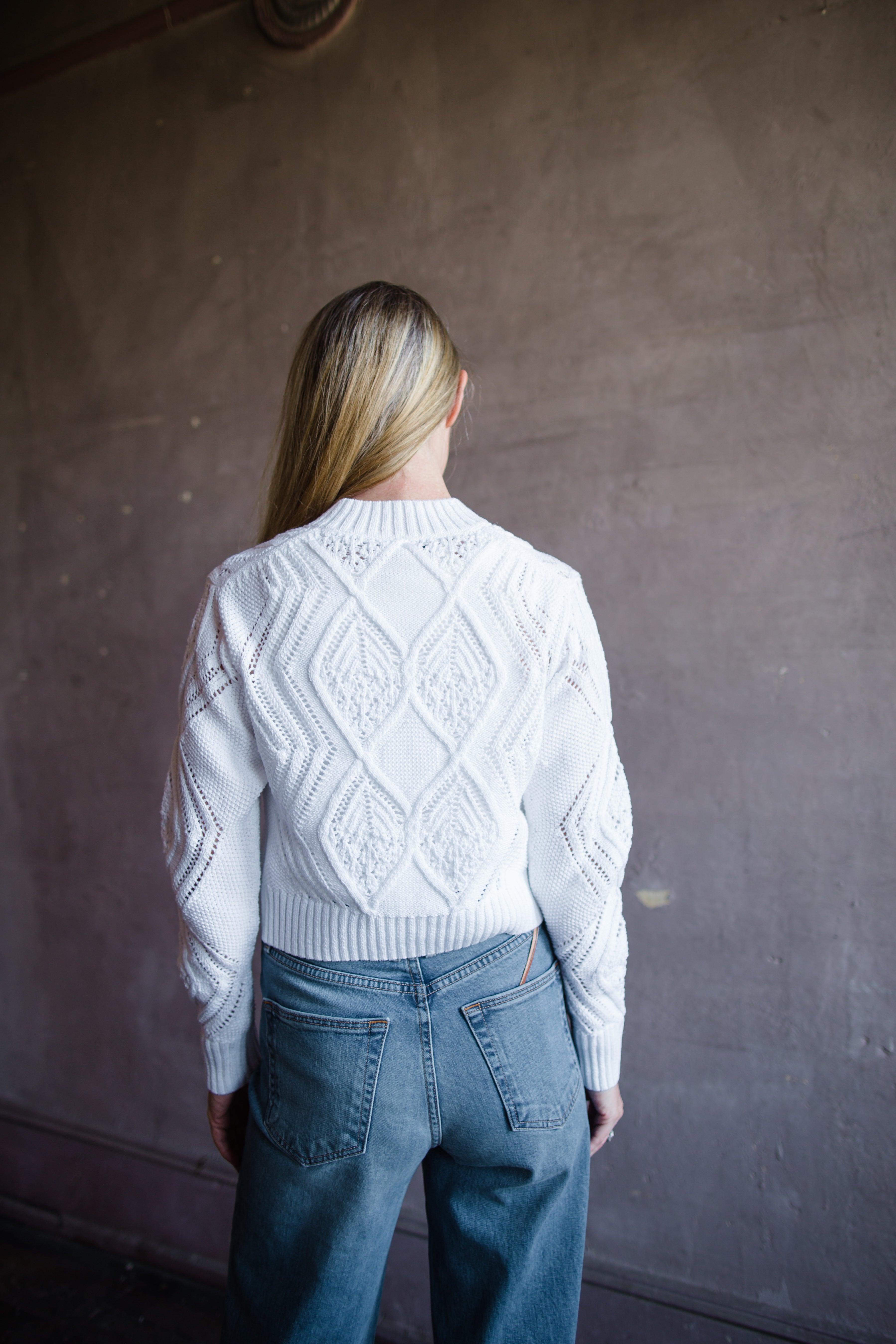 Image featuring a woman wearing the light Italian cotton cardigan sweater from Vince with an open knit in an intricate diamond motif and cut with a slightly cropped length in white.