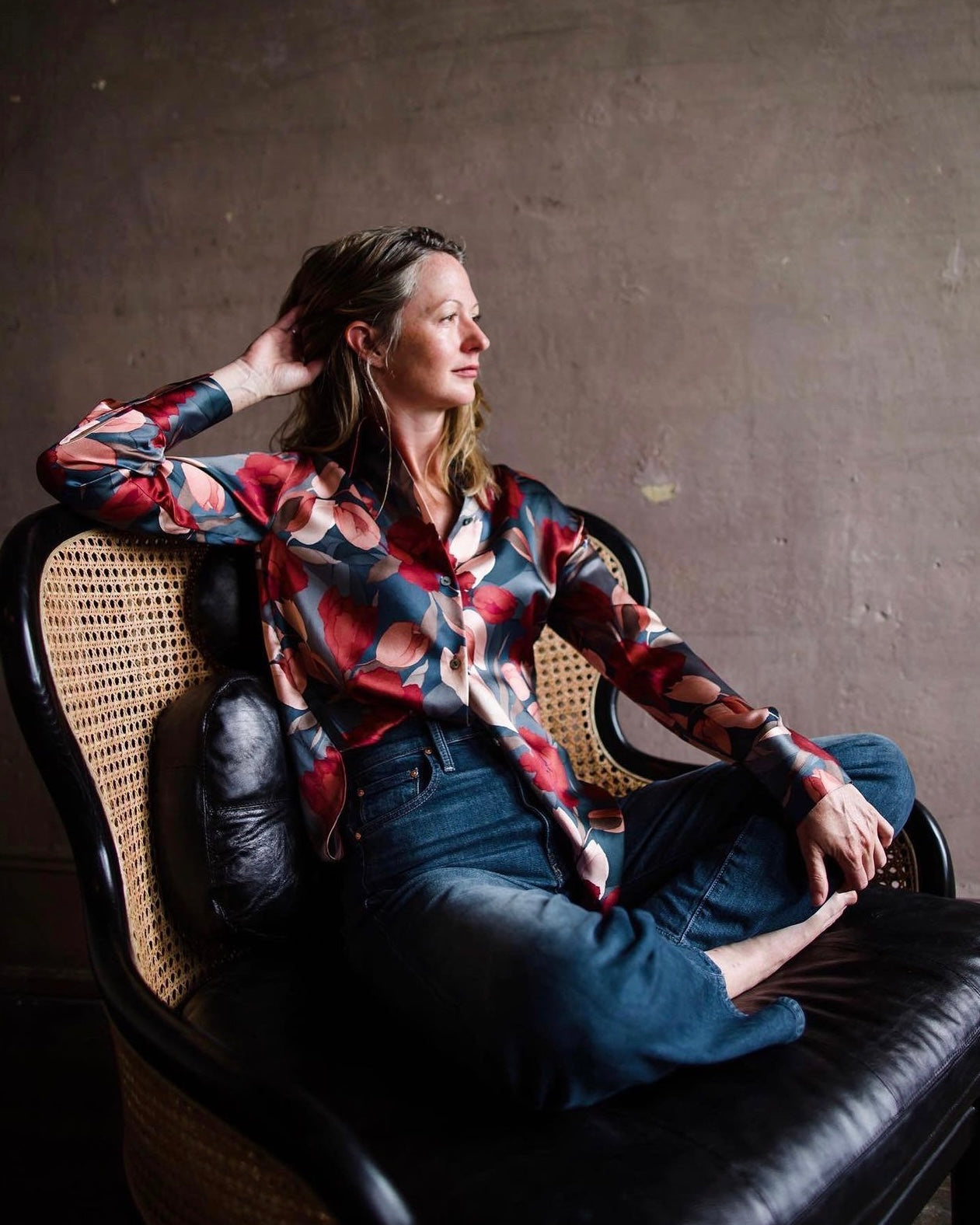 Image featuring a woman wearing the Noveau silk blouse by Vince with a button front, long sleeves and relaxed fit with an allover burgundy and coral bold magnolia floral pattern on a navy background.