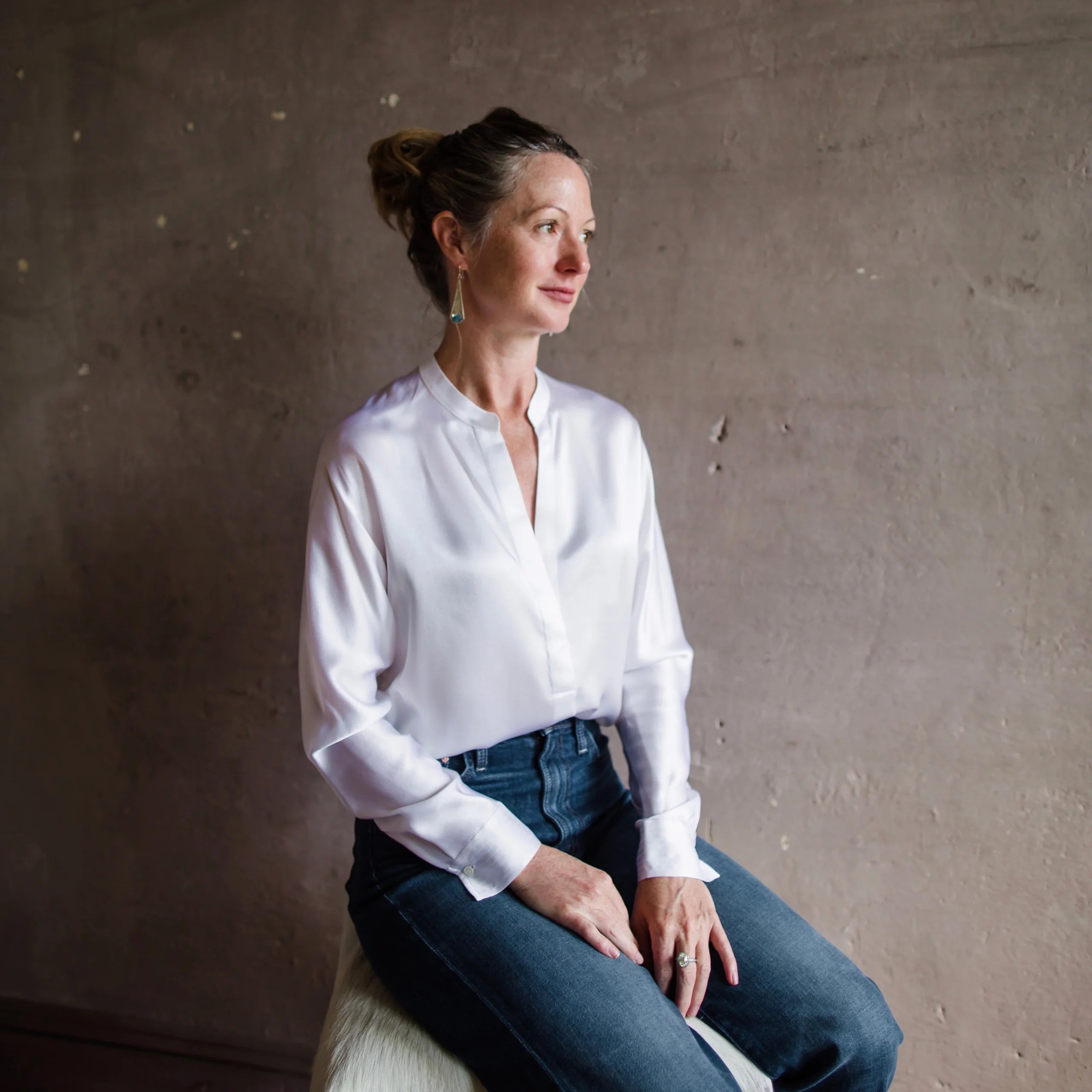 Image featuring a woman wearing the Vince button down bright white silk blouse features a dolman neckline, long sleeves.