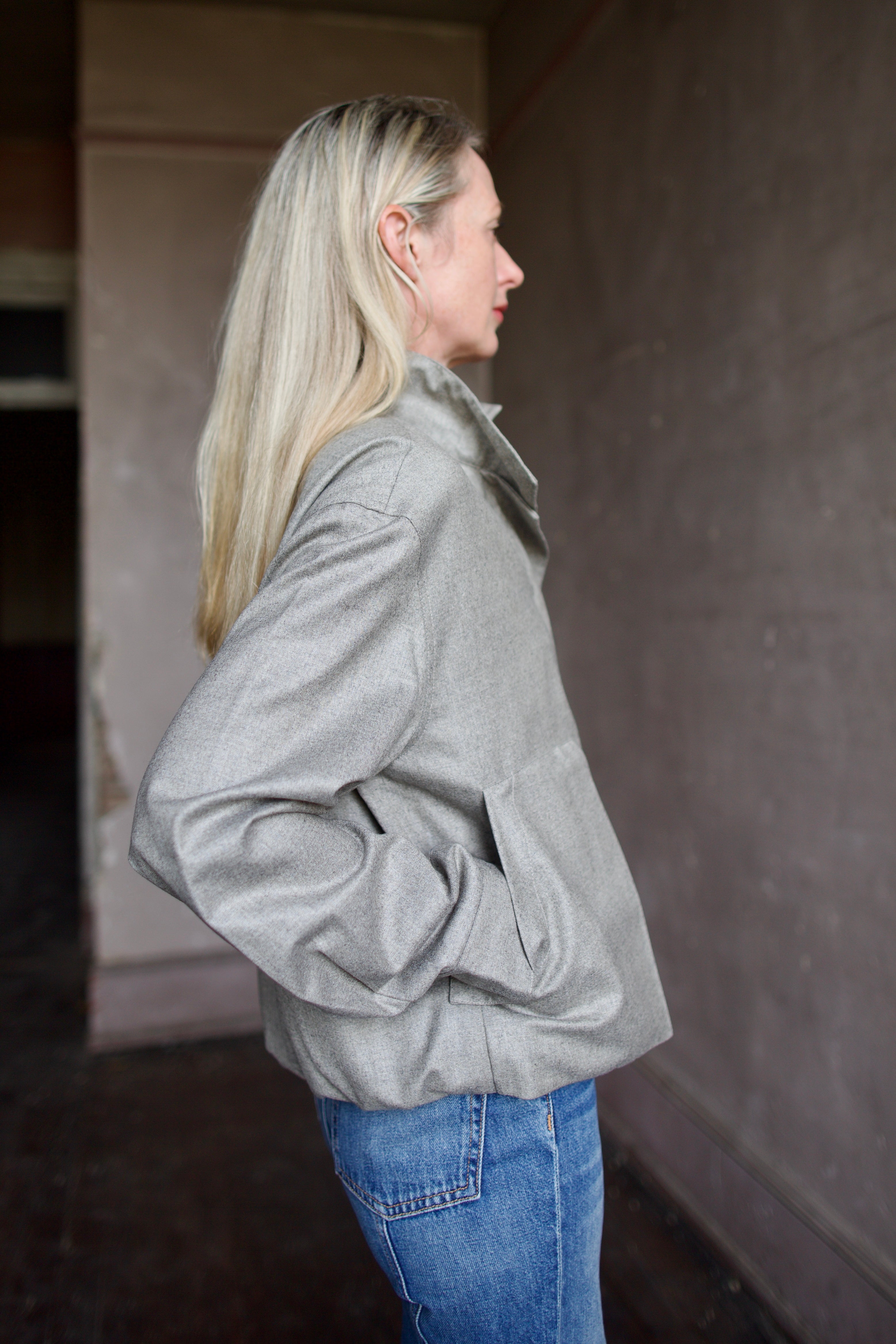 Mature model wearing a modern design light weight virgin wool gray jacket by We-AR4 with front pockets