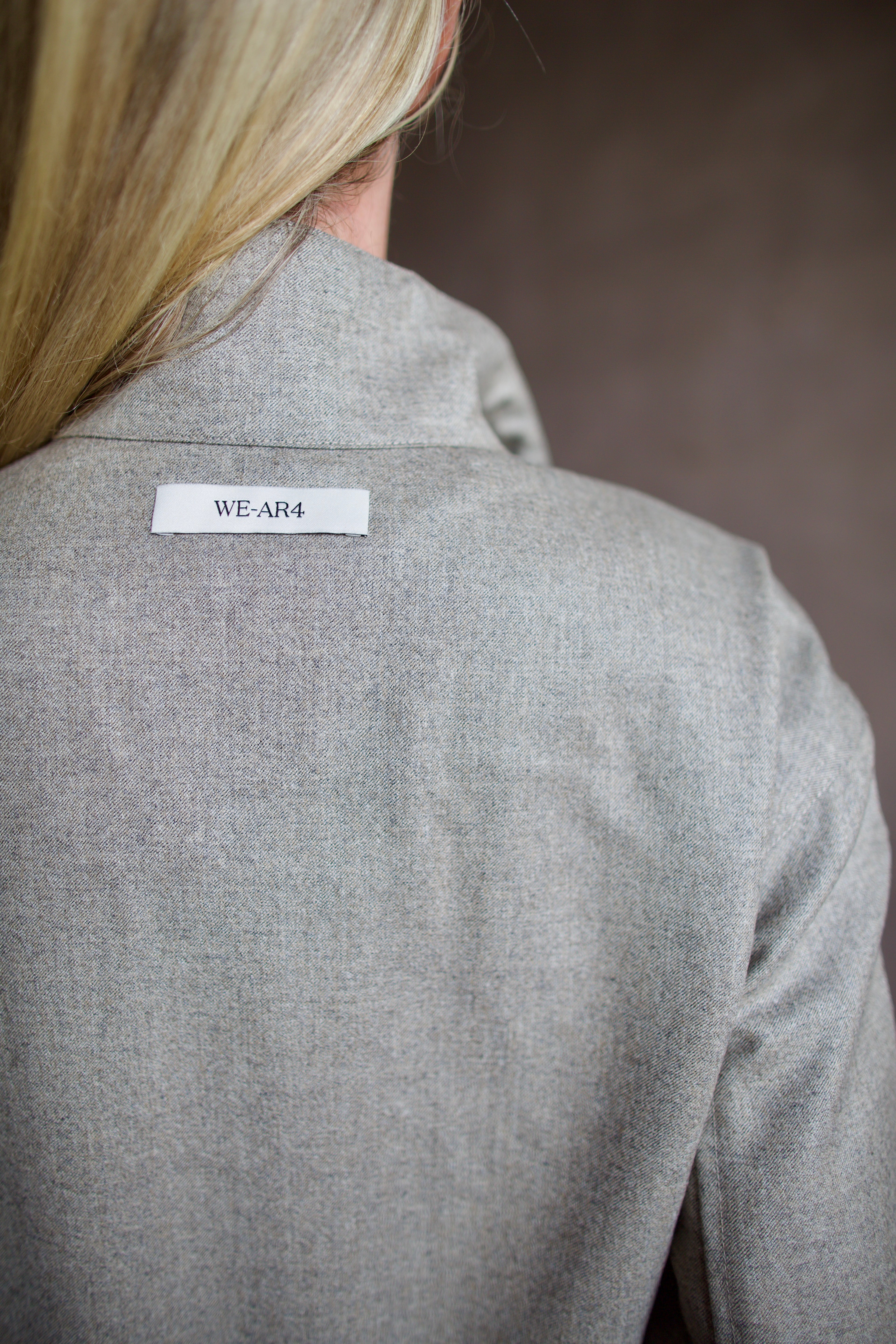 Mature model wearing a modern design light weight virgin wool gray jacket by We-AR4 with front pockets