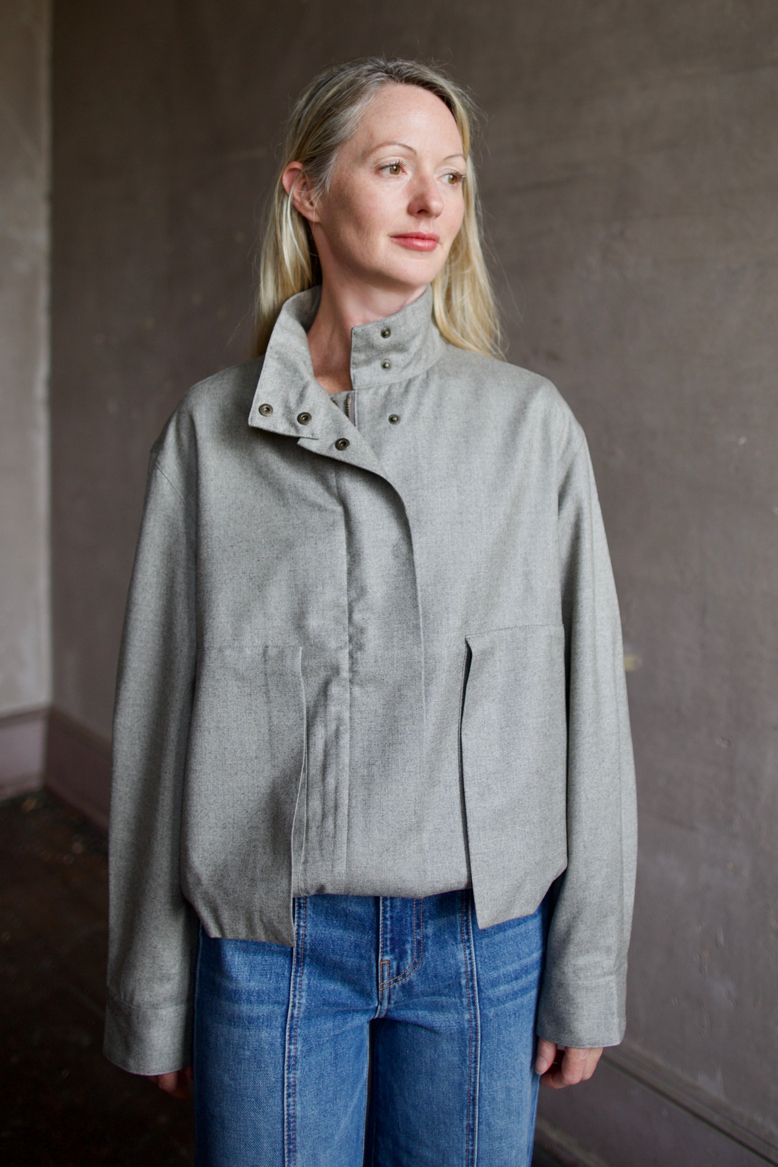 Mature model wearing a modern design light weight virgin wool gray jacket by We-AR4 with front pockets