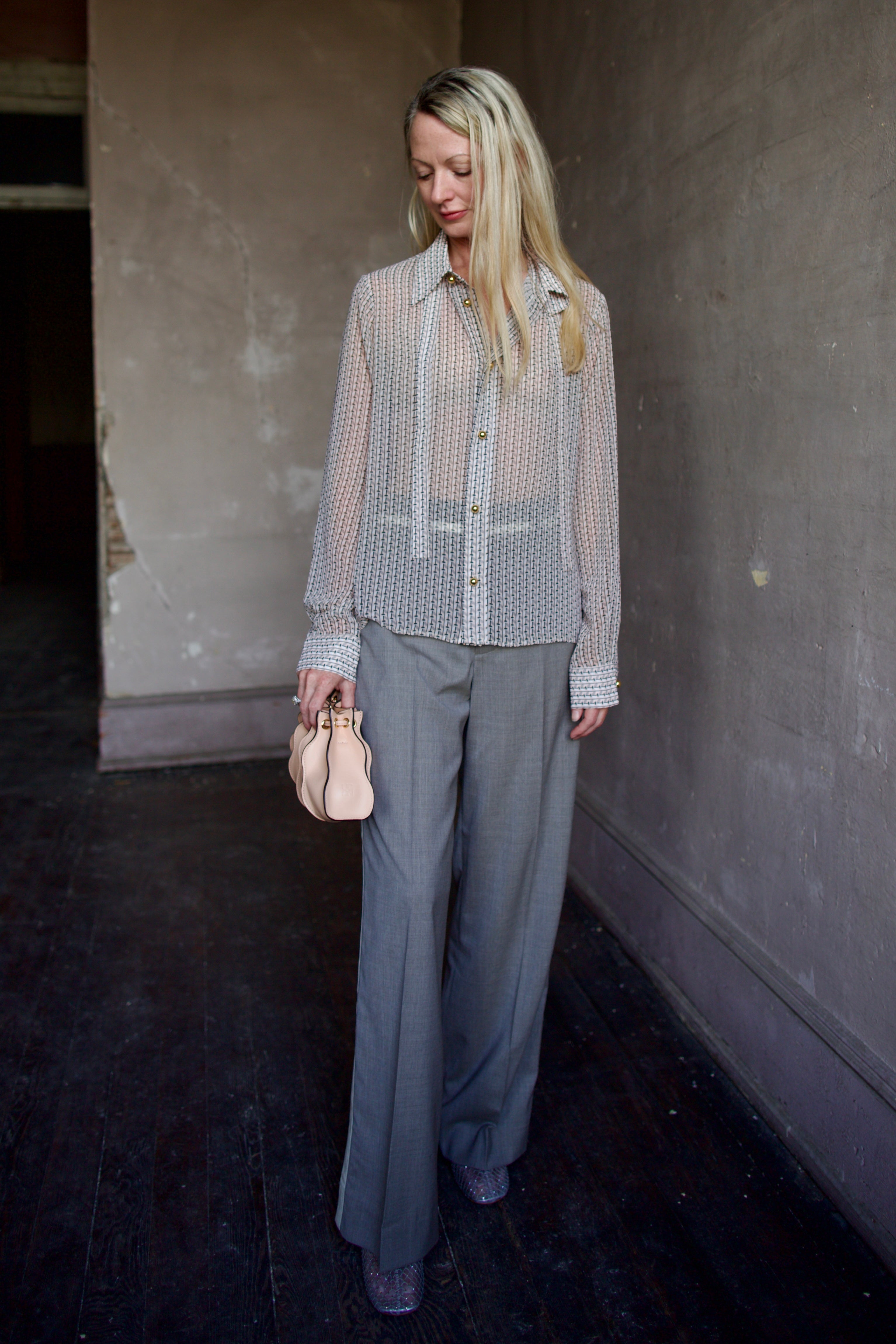 Mature model wearing a sheer geometric shirt with round gold metal buttons by designer WE-AR4