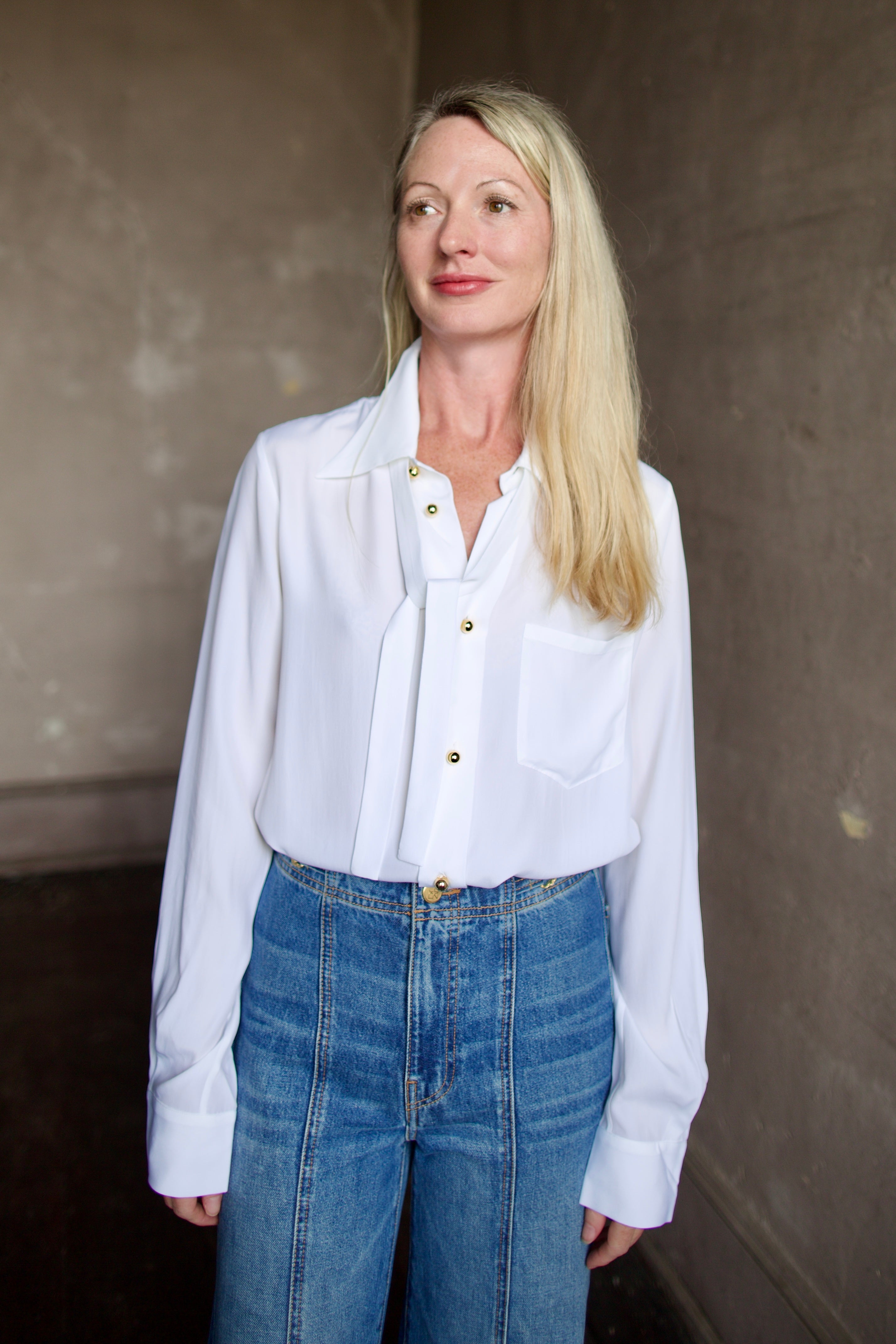 Mature model wearing a white shirt with round gold metal buttons by designer shirt by WE-AR4