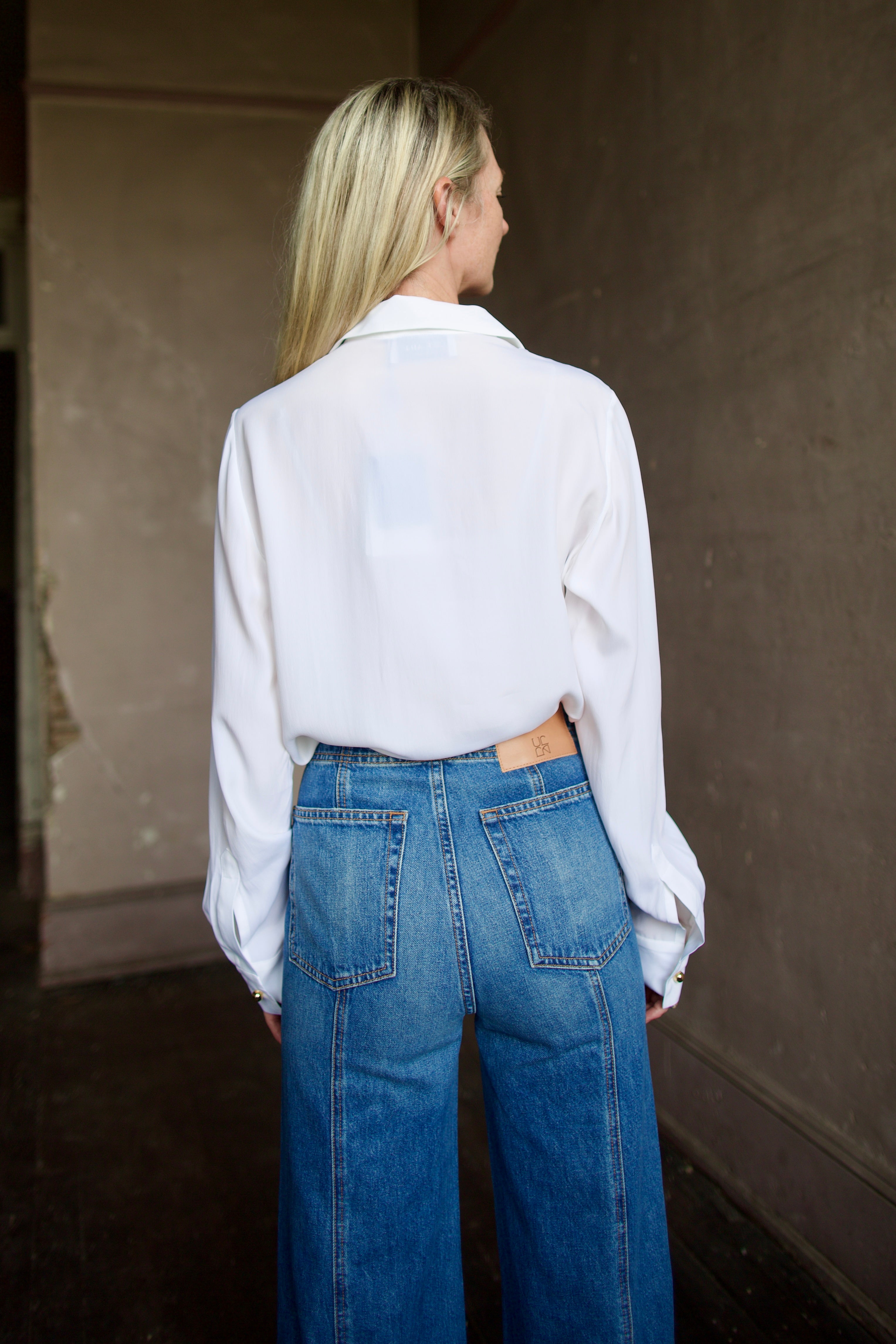 Mature model wearing a white shirt with round gold metal buttons by designer shirt by WE-AR4