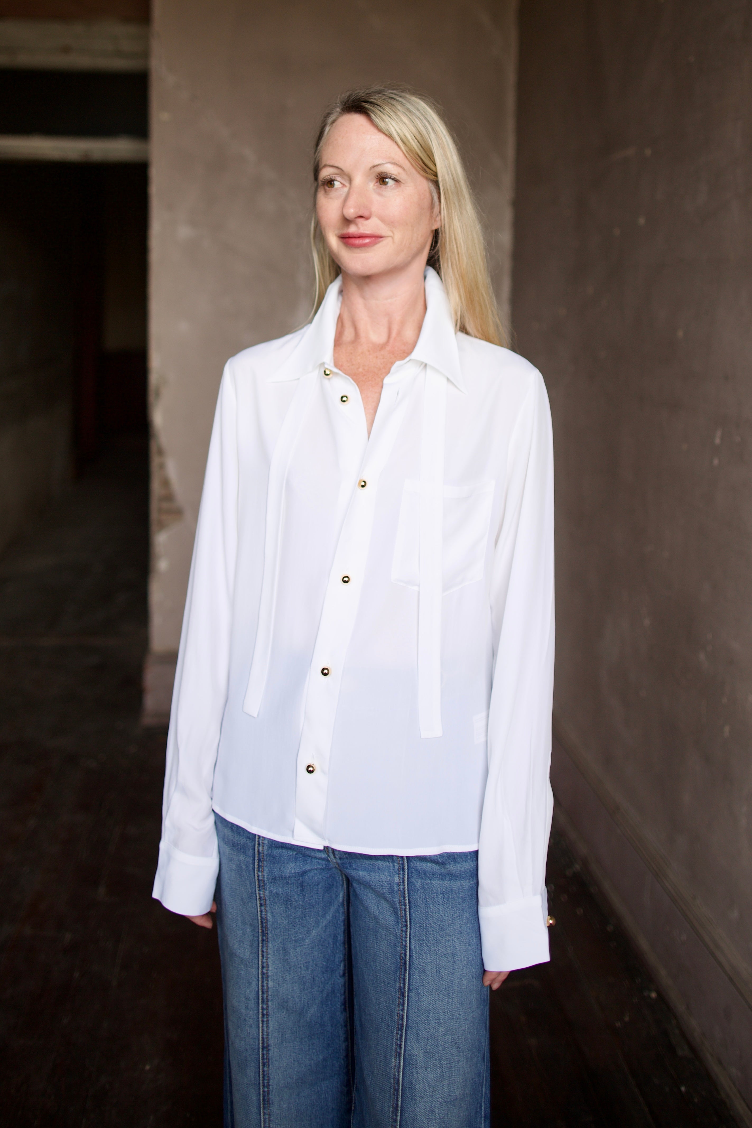 Mature model wearing a white shirt with round gold metal buttons by designer shirt by WE-AR4