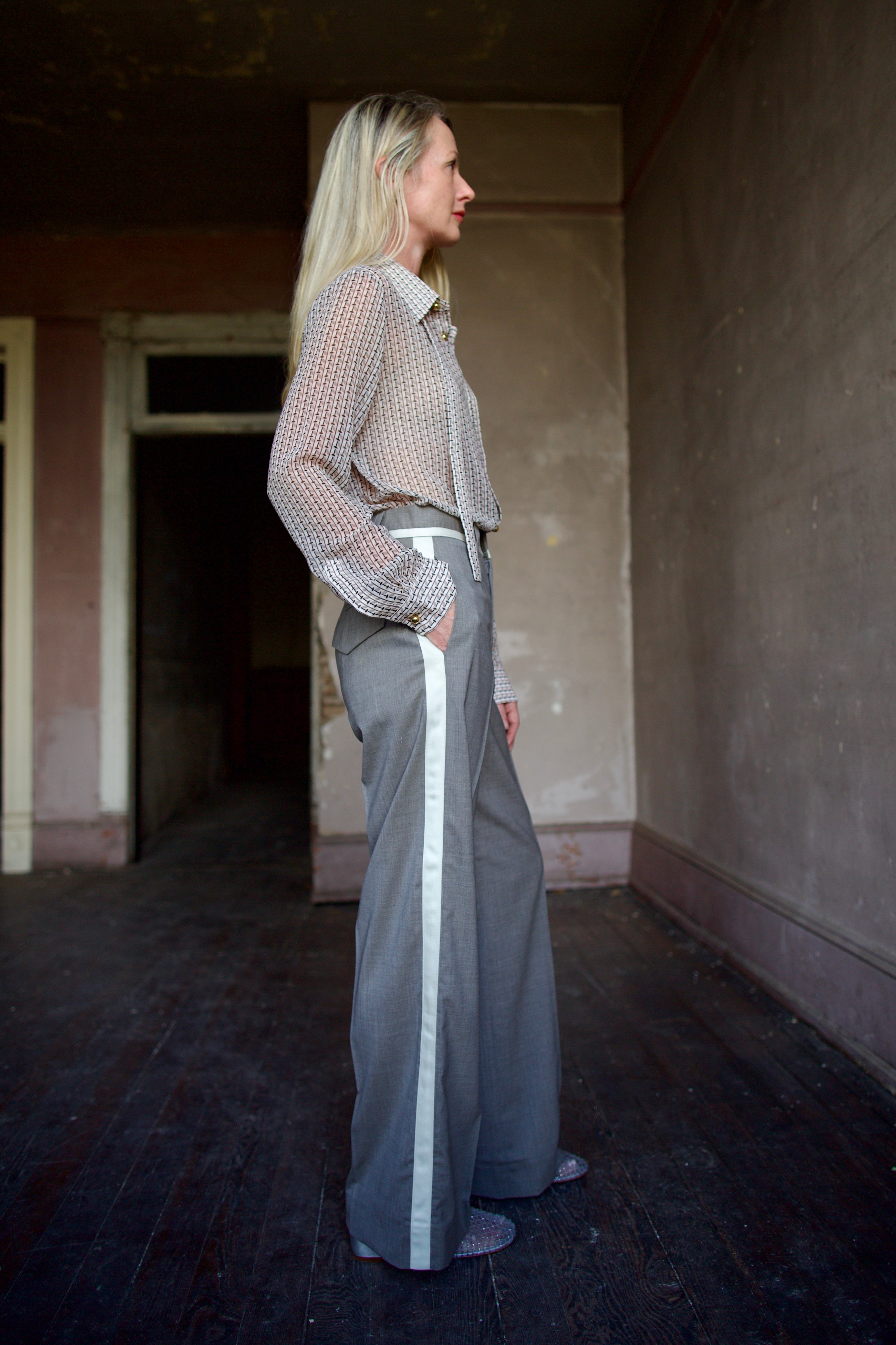 Mature model wearing virgin wool taupe tuxedo trousers with cream details by luxury designer WE-AR4