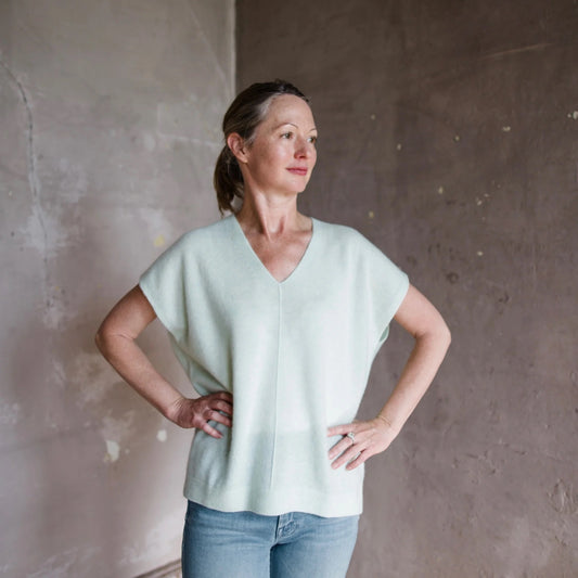 Image featuring a woman wearing  the White + Warren oversized cashmere poncho in mint green with a v-neck and short sleeves.