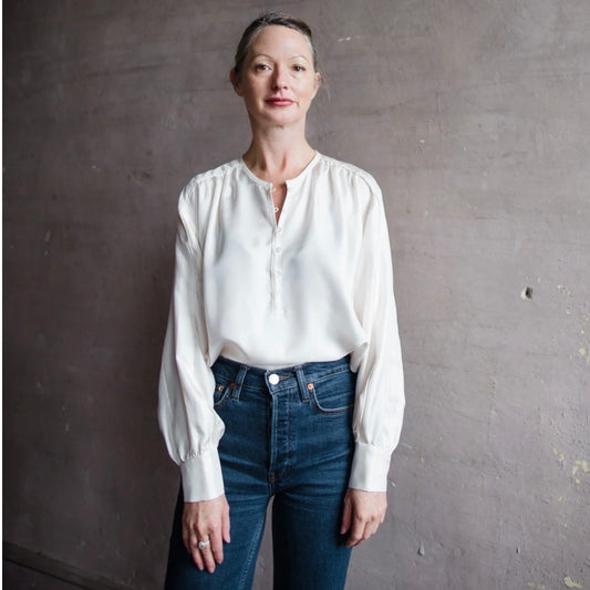 Image featuring a woman wearing the Xirena Jacqueline ivory blouse with a dolman neckline and long sleeves in a winter weight silk.