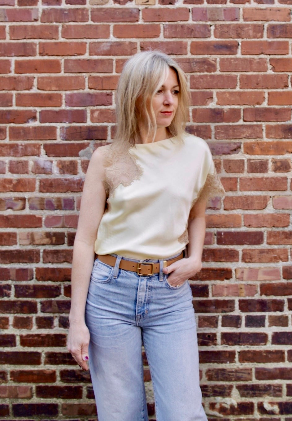 Mature woman wearing the yellow and beige ALC Alessia Top with open neckline, asymmetrical fit and lace detailing