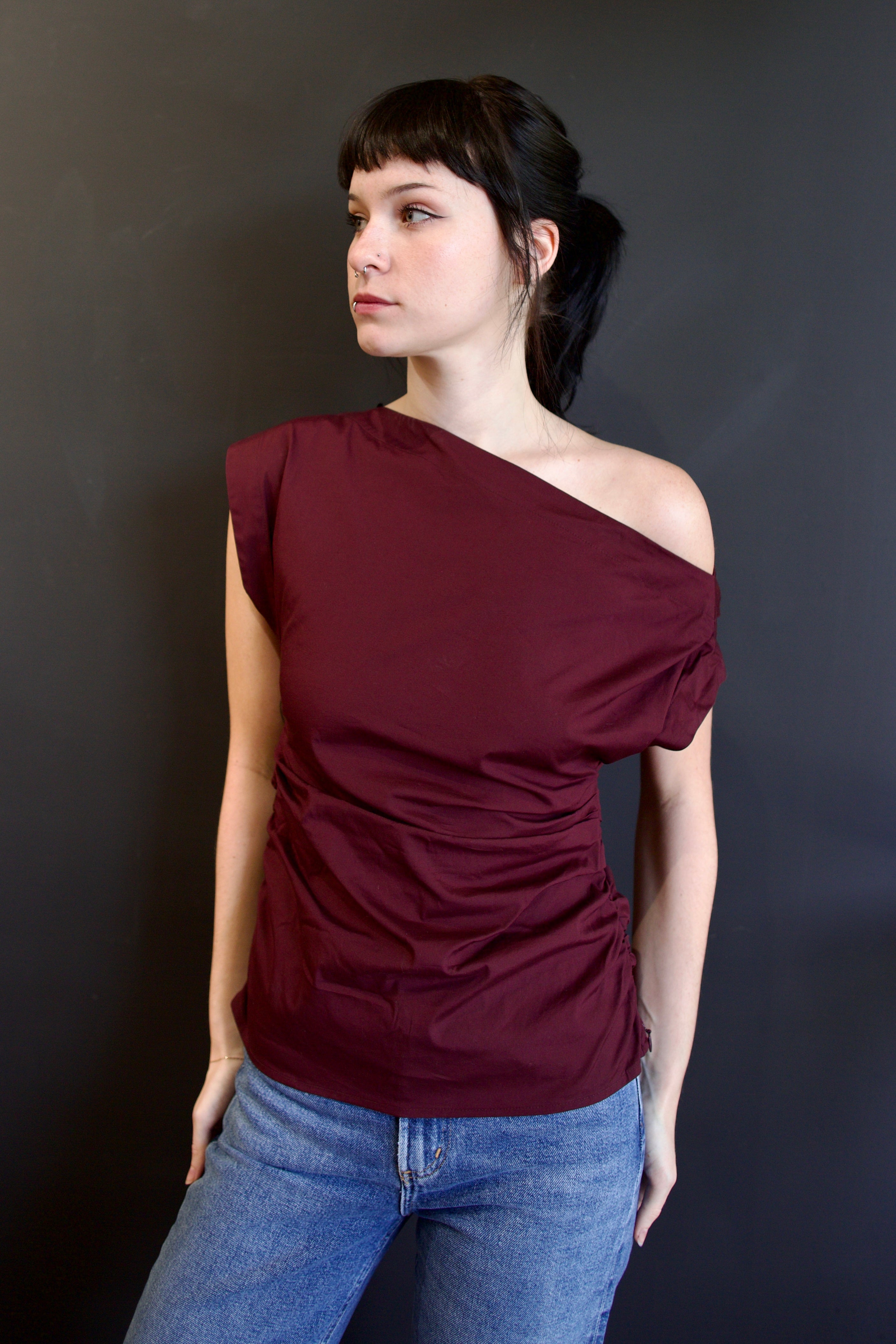Model wearing ALC Nara top in burgundy with one-shoulder asymmetrical design and rushing at waist
