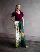 Image featuring a woman wearing the linen blend Aggie pants by Alemais with an elastic waist, wide leg and an allover tropical floral print.