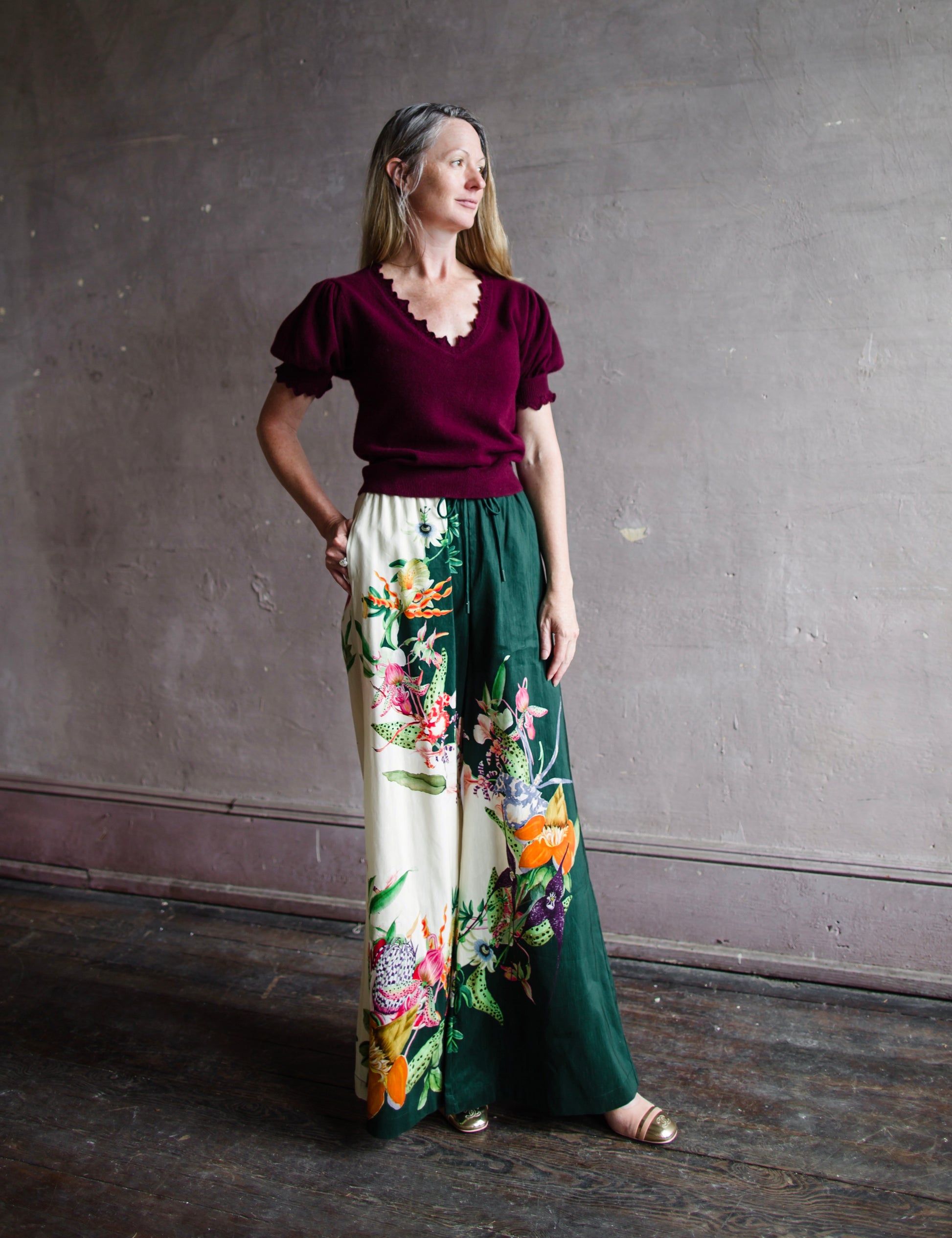 Image featuring a woman wearing the linen blend Aggie pants by Alemais with an elastic waist, wide leg and an allover tropical floral print.