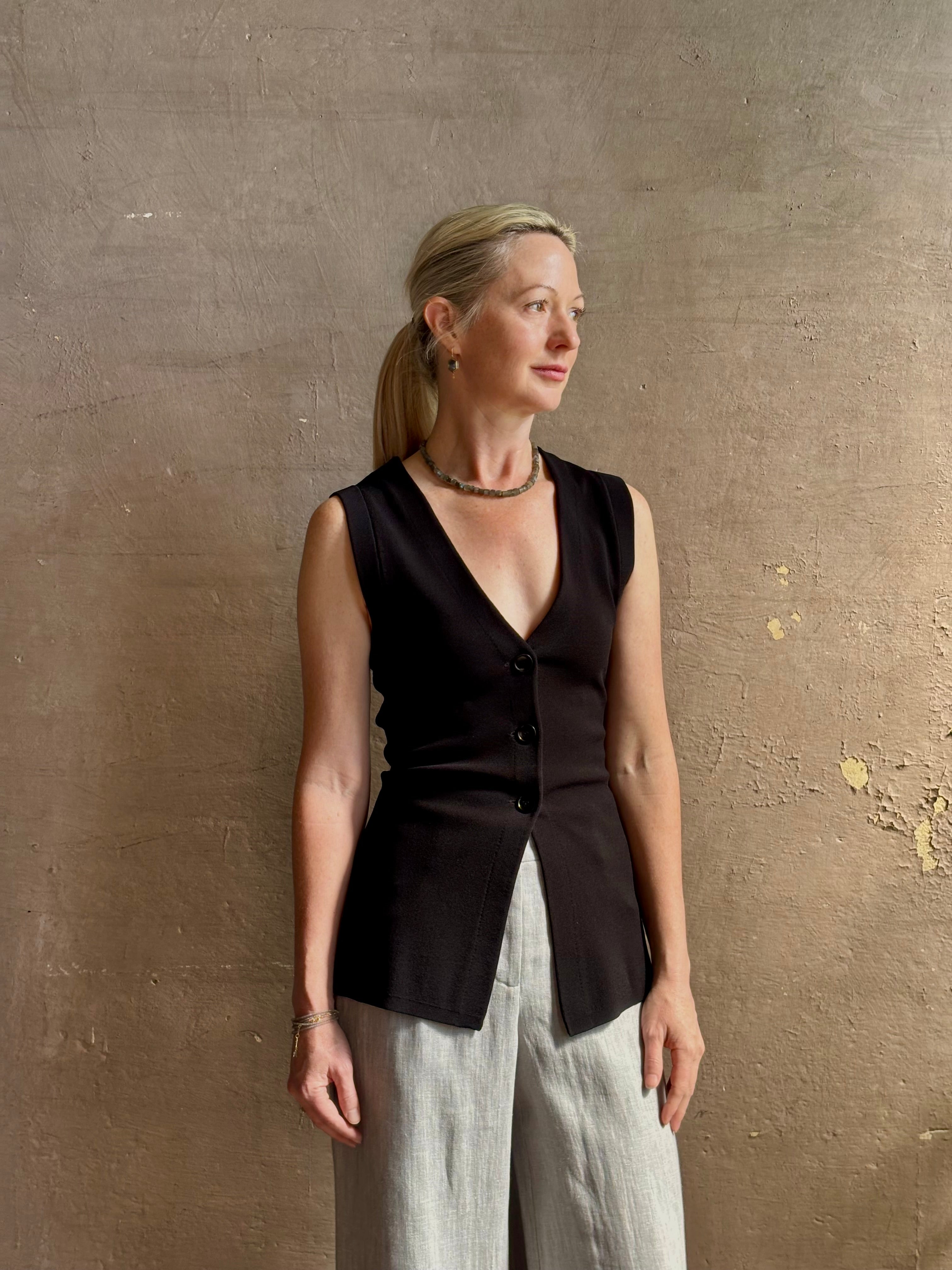 Mature woman wearing a flattering Apiece Apart Marca Knit Top in black with 3 button closure, v- neck and sleeveless