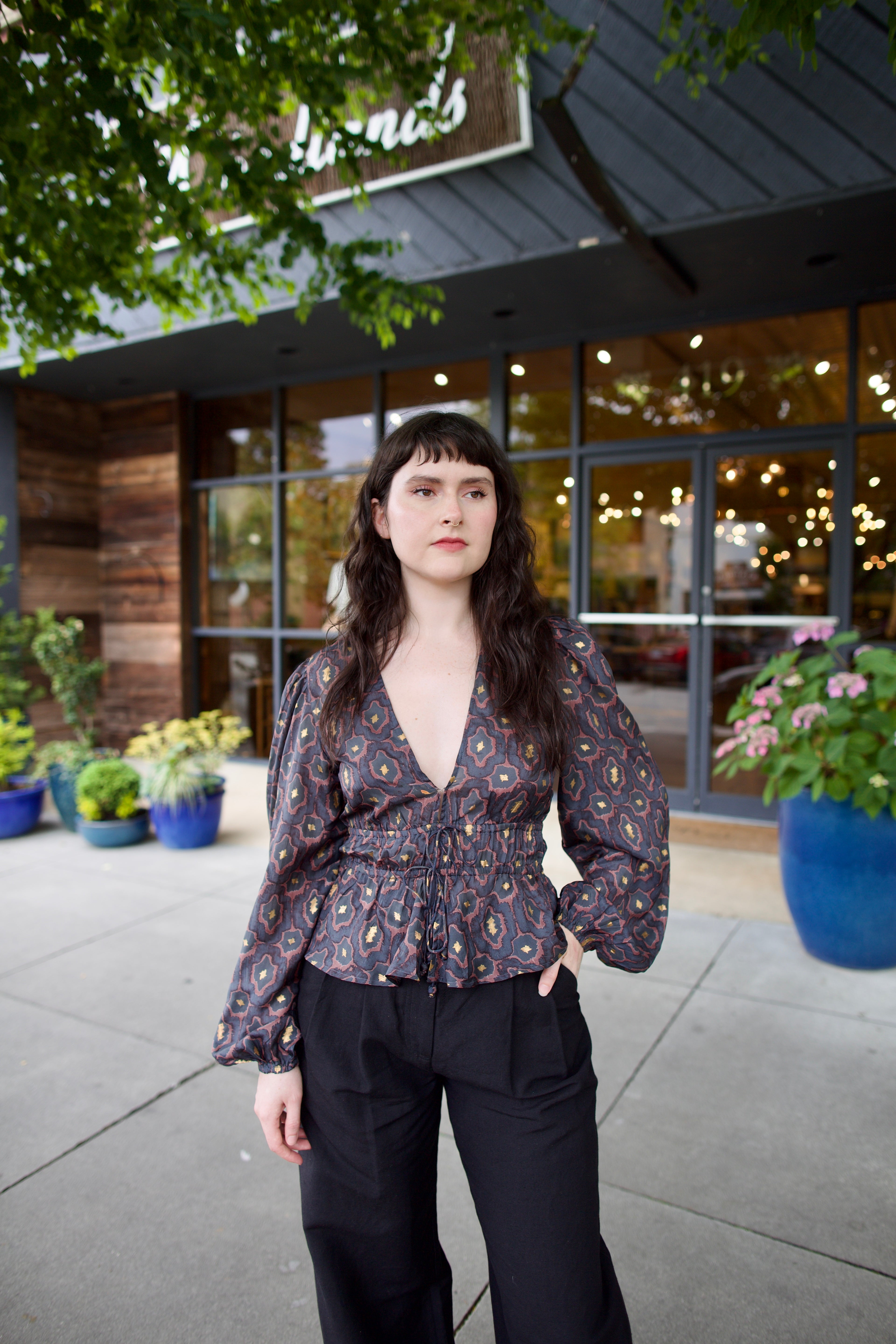 Image of a woman wearing the Hannah Artwear silk Lola Blouse with peplum, long sleeves, v-neck, blockprint and hand applied gold leaf