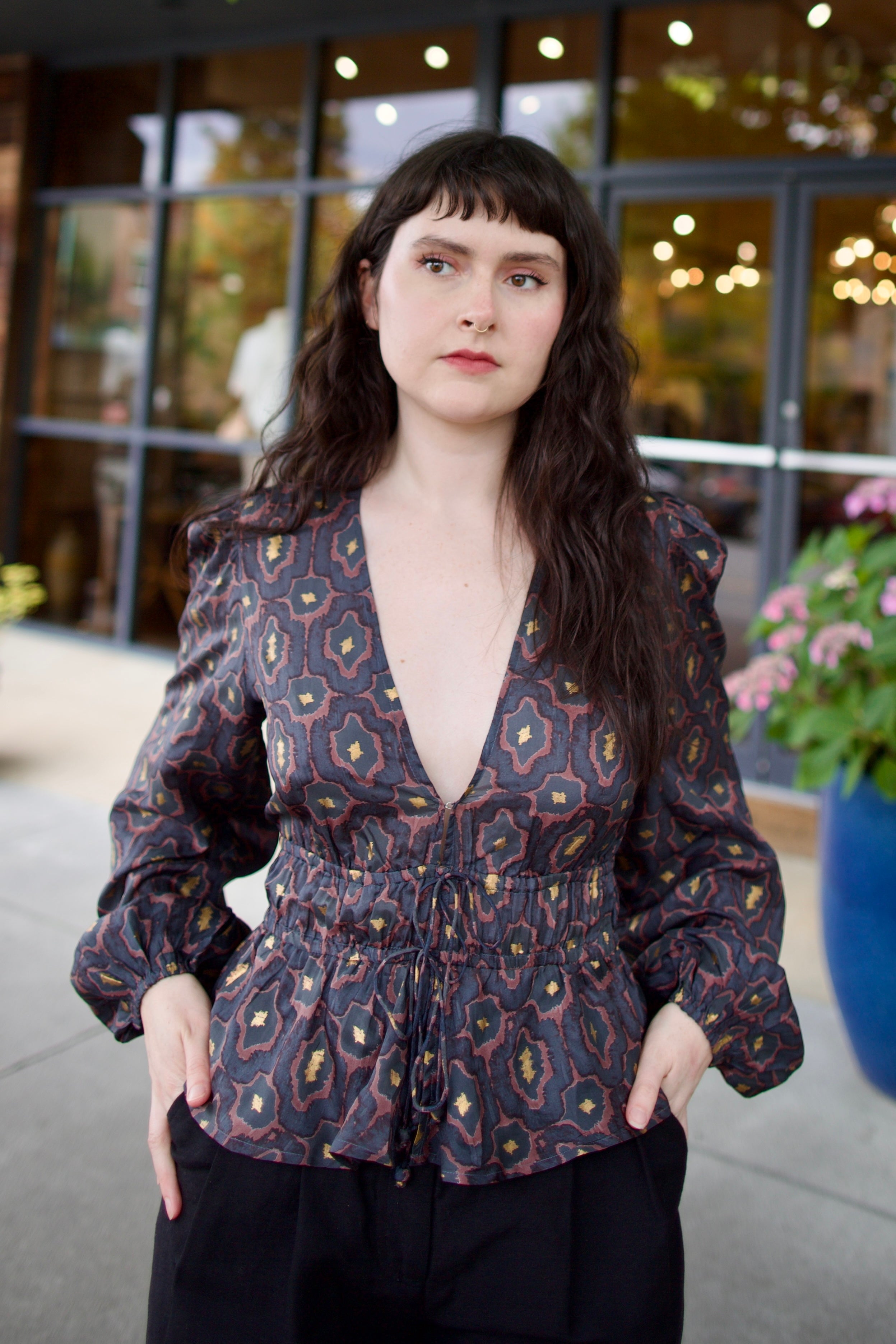Image of a woman wearing the Hannah Artwear silk Lola Blouse with peplum, long sleeves, v-neck, blockprint and hand applied gold leaf