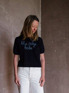 Image featuring a woman wearing the navy blue cashmere sweater by Lingua Franca with a crew neckline, short sleeves and embroidered "blue ridge babe".
