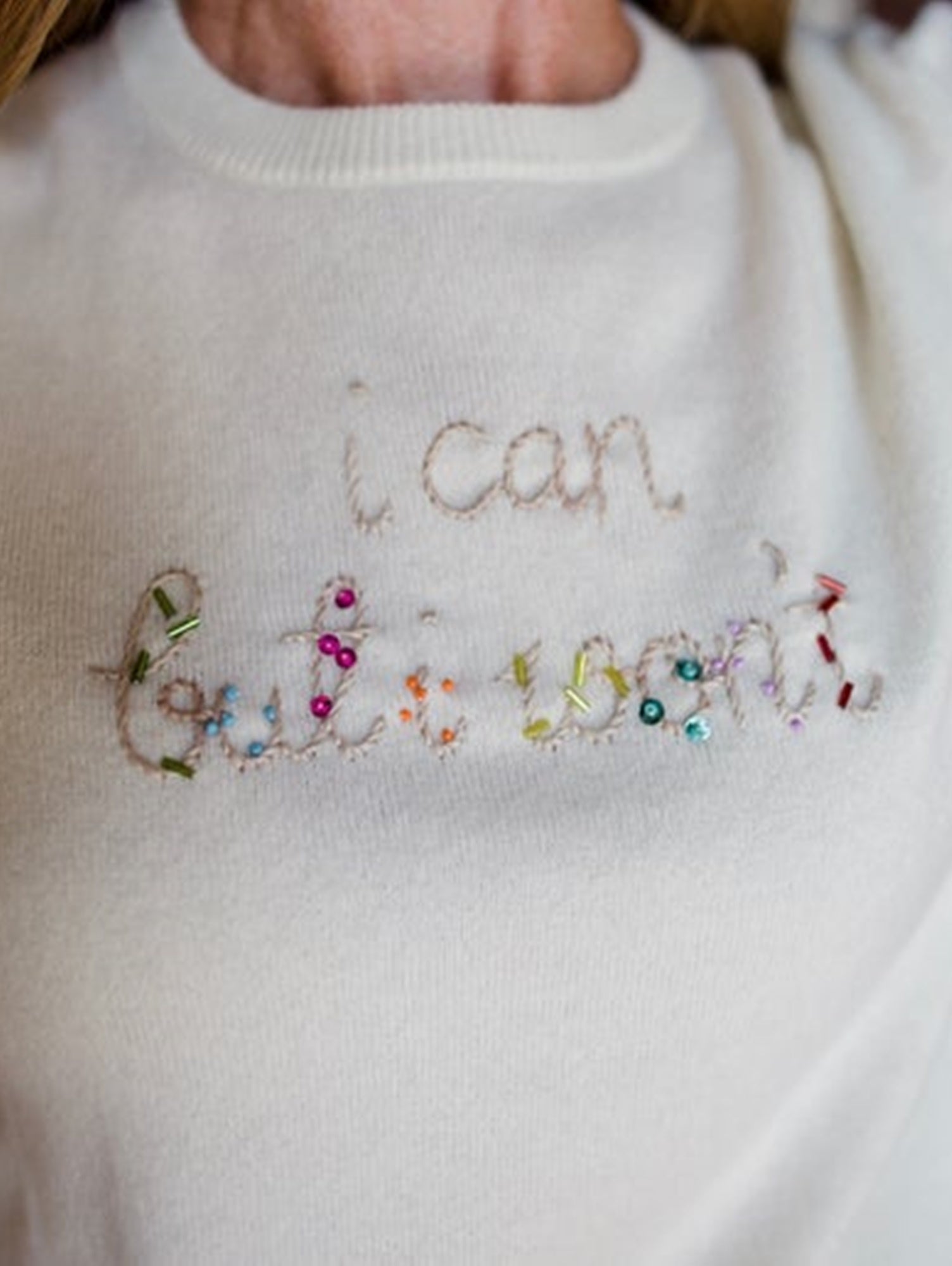 Image featuring a woman wearing the cream cashmere sweater by Lingua Franca with a crew neckline and "I can but I won't" embroidered on the front.