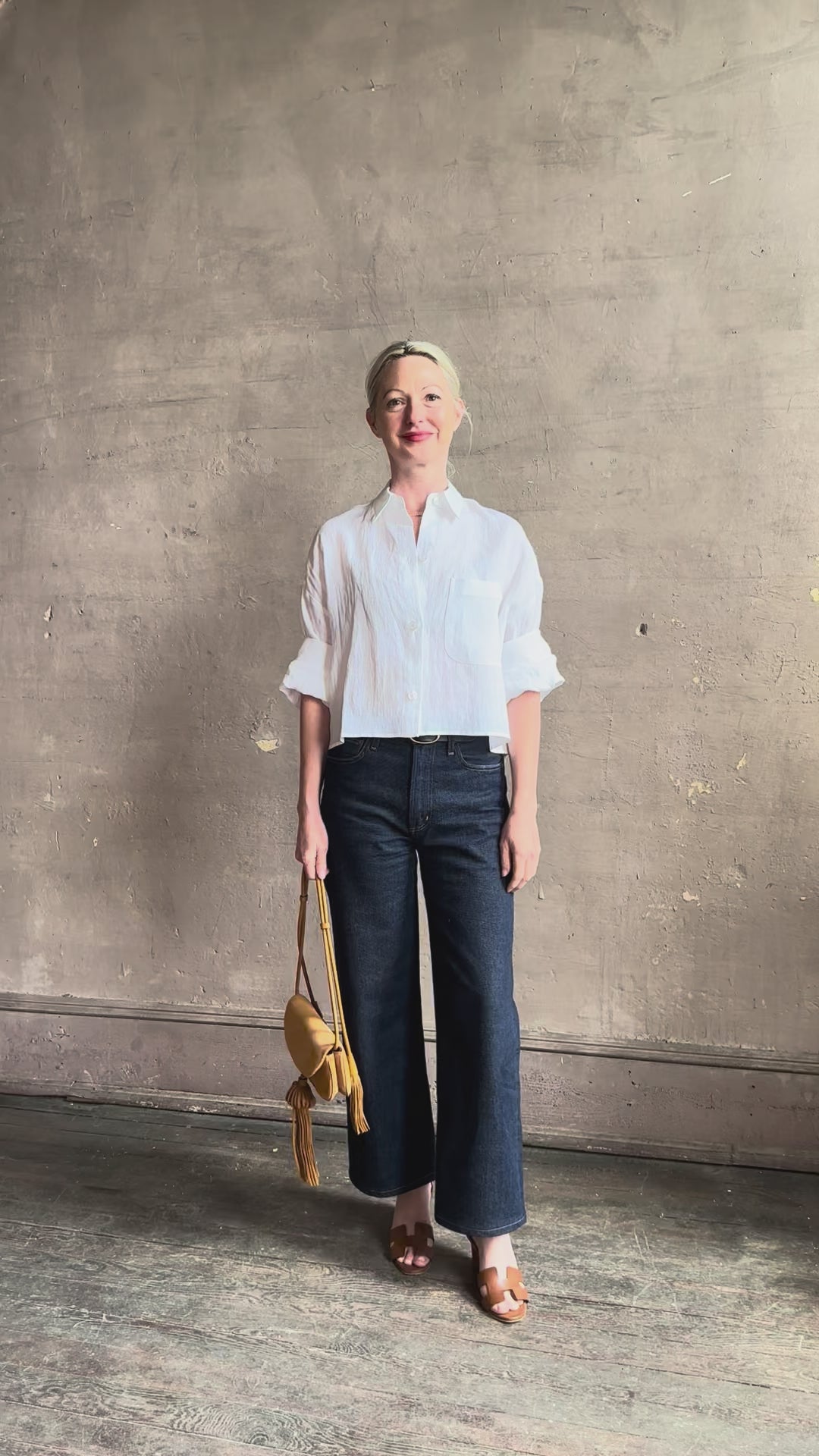 Mature woman reviewing the Next Ex Top from TWP rendered in a crisp white and crafted from premium linen in New York City, this luxury linen top offers effortless cool girl with an intentionally oversized boxy silhouette with tailored half sleeve cuffs, collared button - down menswear inspired with a single front pocket