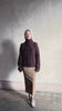 Video reviewing Guest in Residence’s Super Cloud T Neck in Fig cashmere-silk boucle knit with a cable pattern and oversized funnel neck. Jewel-toned, cloud-soft statement warmth
