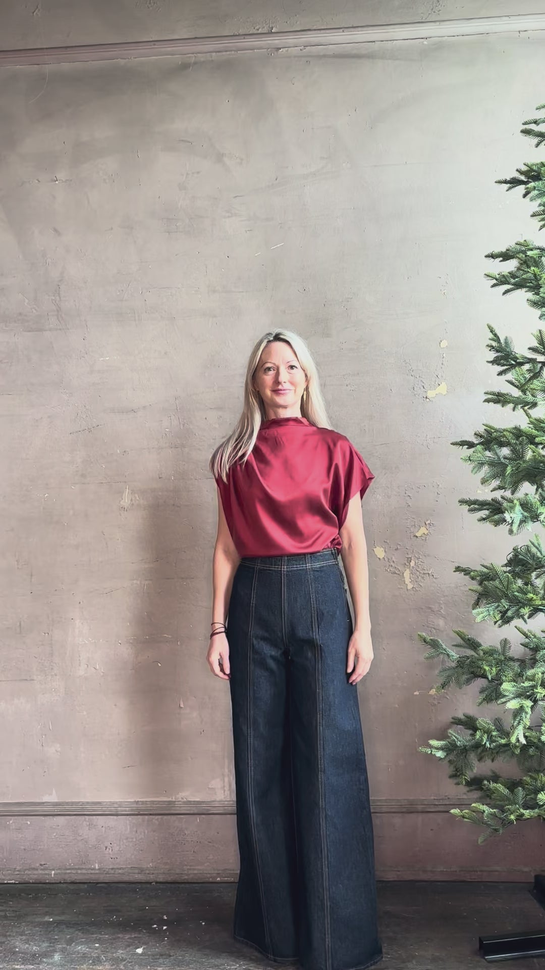 Mature woman wearing ULLA JOHNSON Bianca dark wash tigris rigid denim with a flat front, contrasting front seam details, high rise, wide leg, and side seam concealed zipper closure