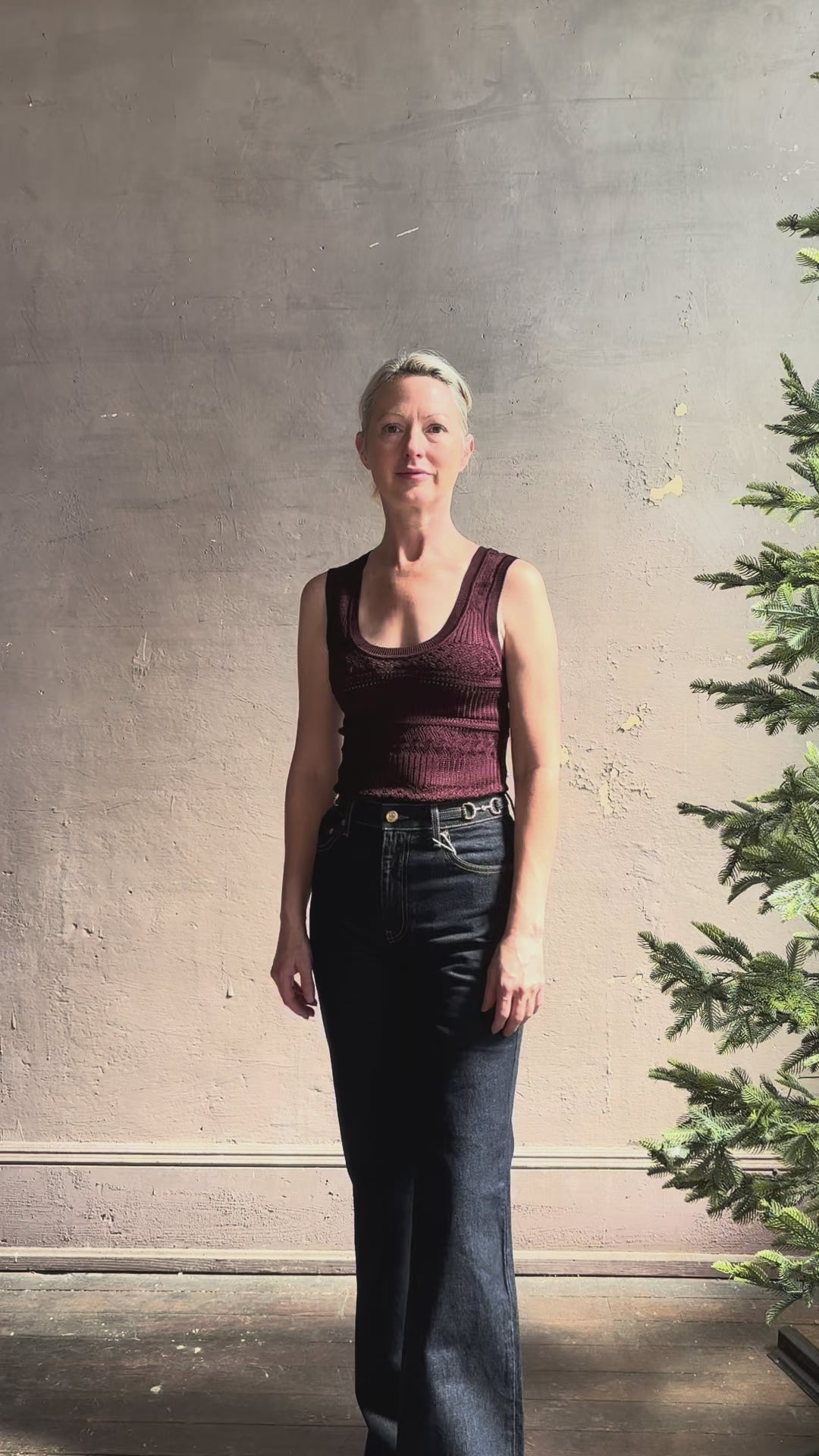 Mature woman reviewing designer denim Colette Straight Leg Jean from Ulla Johnson offering American-made craftsmanship to a clean, timeless, and thoroughly modern everyday silhouette rendered in a sophisticated dark wash and crafted from 100% cotton with twisted buckle detail at waistband