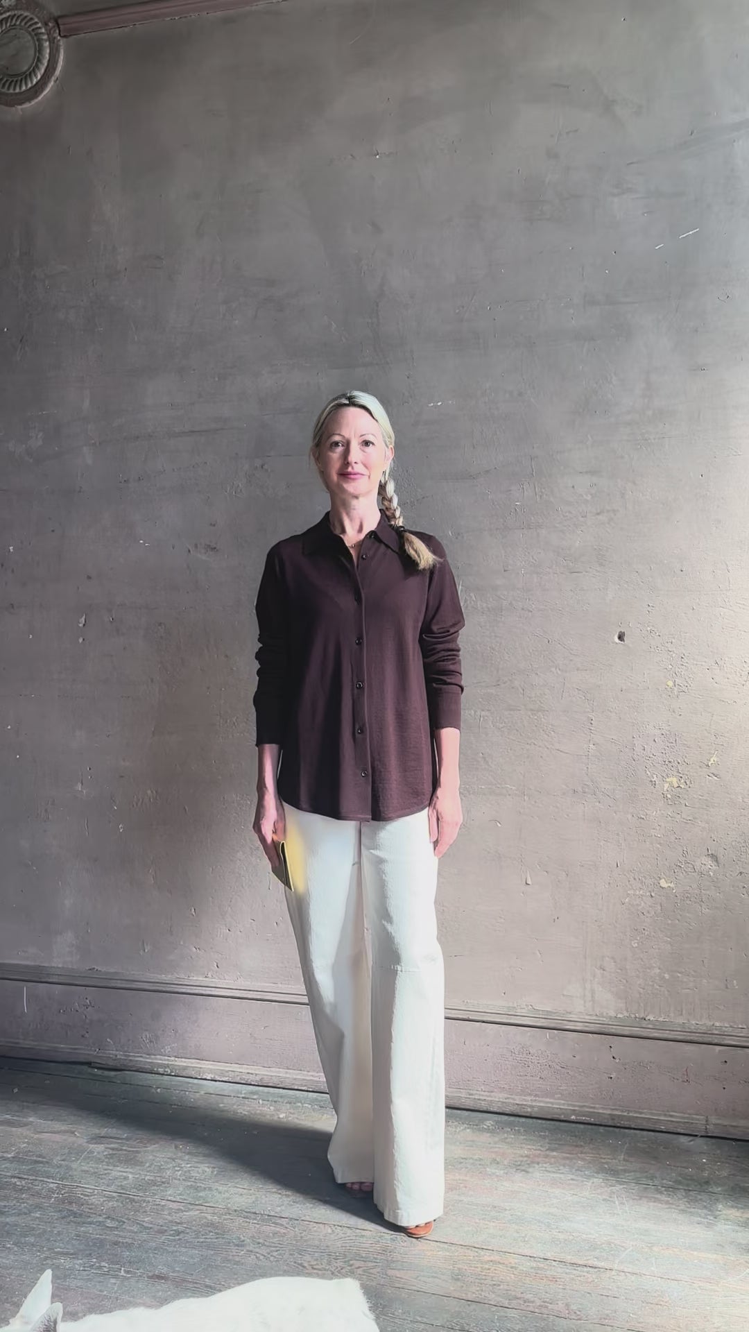 Mature woman reviewing elevated casual wear button front Fonda top by SPRWMN in chocolate brown cashmere with long sleeves and a collar