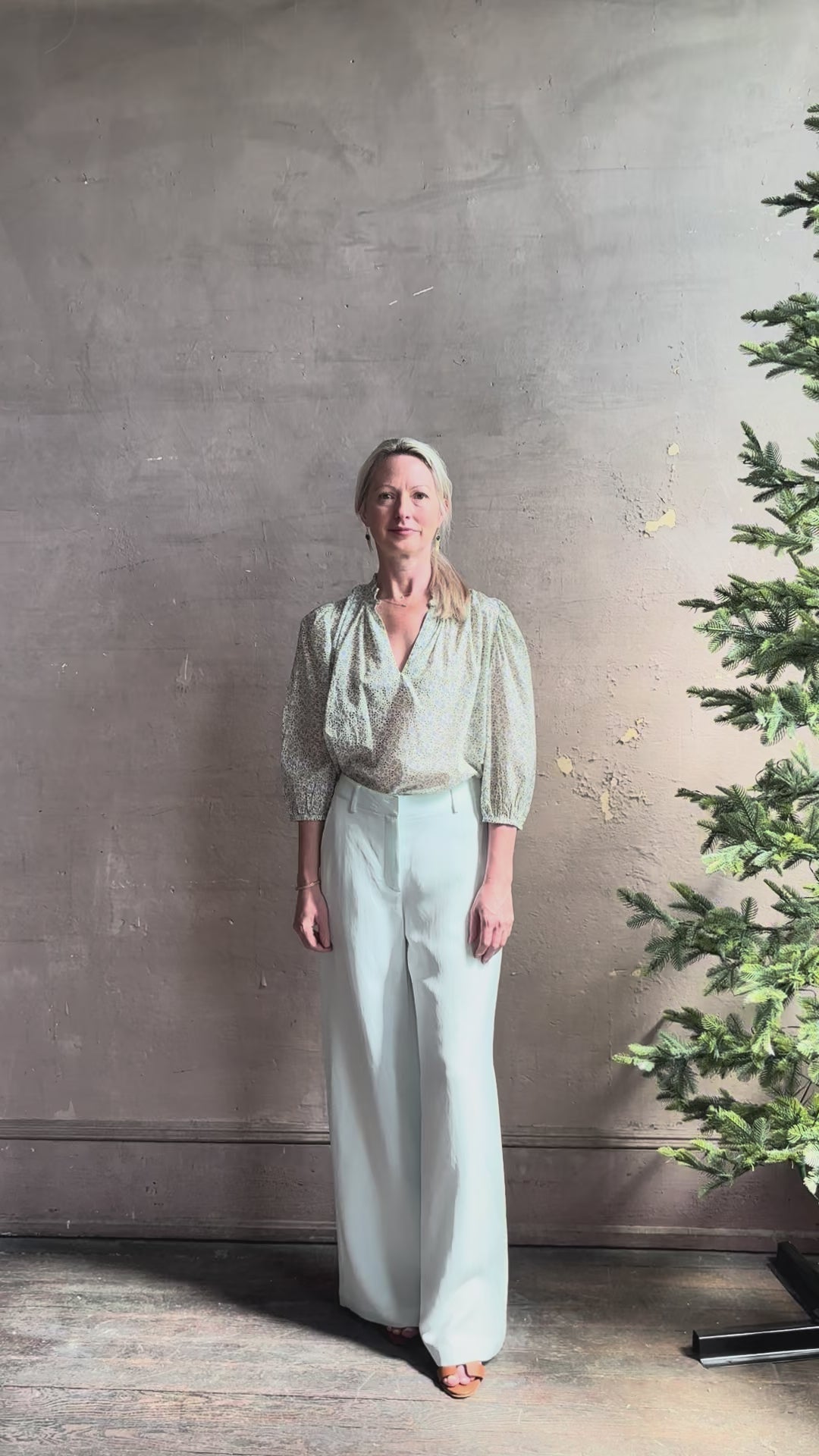 Mature woman reviewing the Orly blouse from Trovata rendered in a charming coastal inspired floral print and crafted from cotton with three quarter sleeves and ruffle lined v-neck