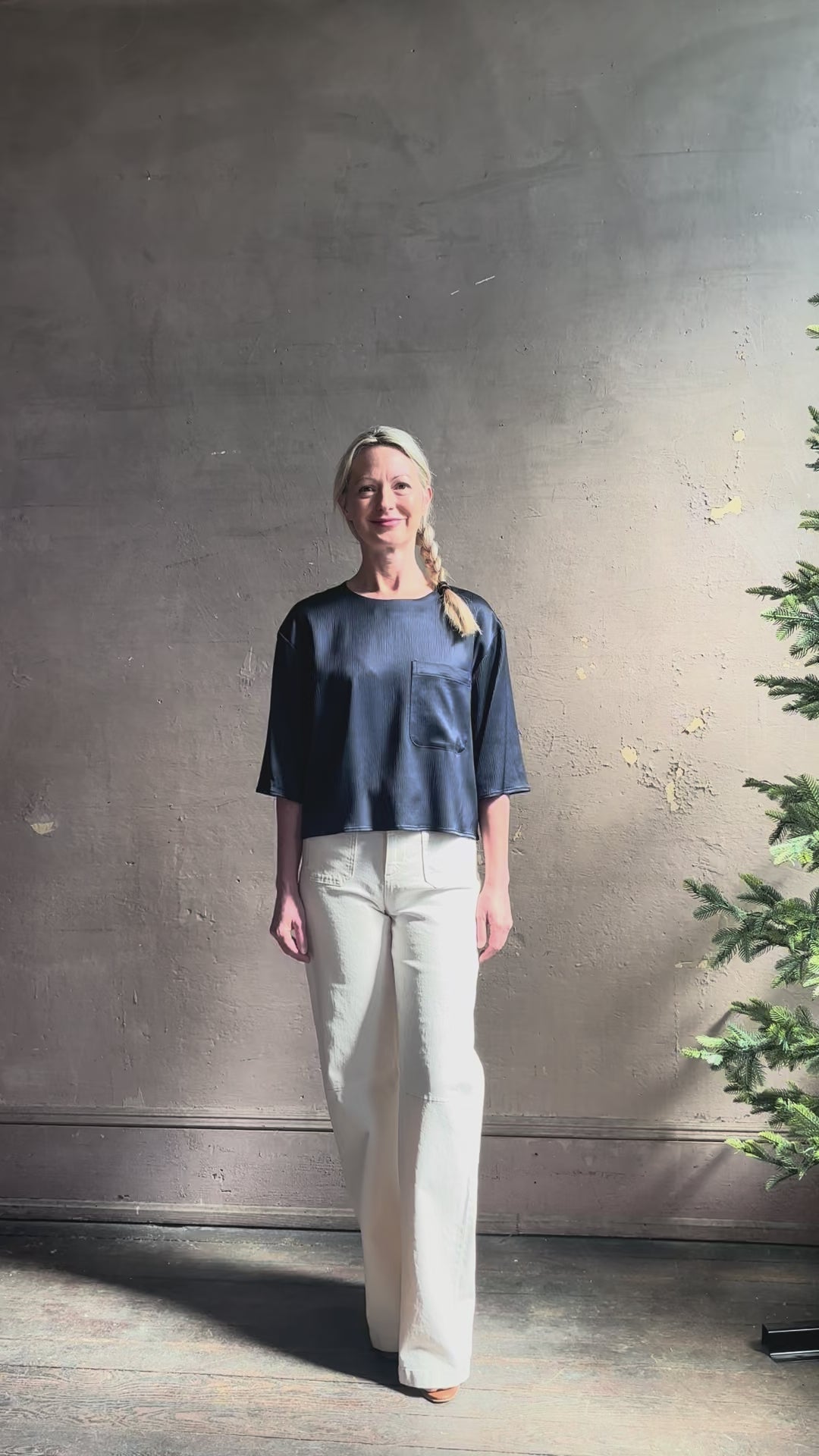 Mature woman reviewing Women's luxury  clothing brand TWP Ex T in premium hammered satin with short sleeves crew neck and a casual front pocket rendered in a beautiful navy blue hue